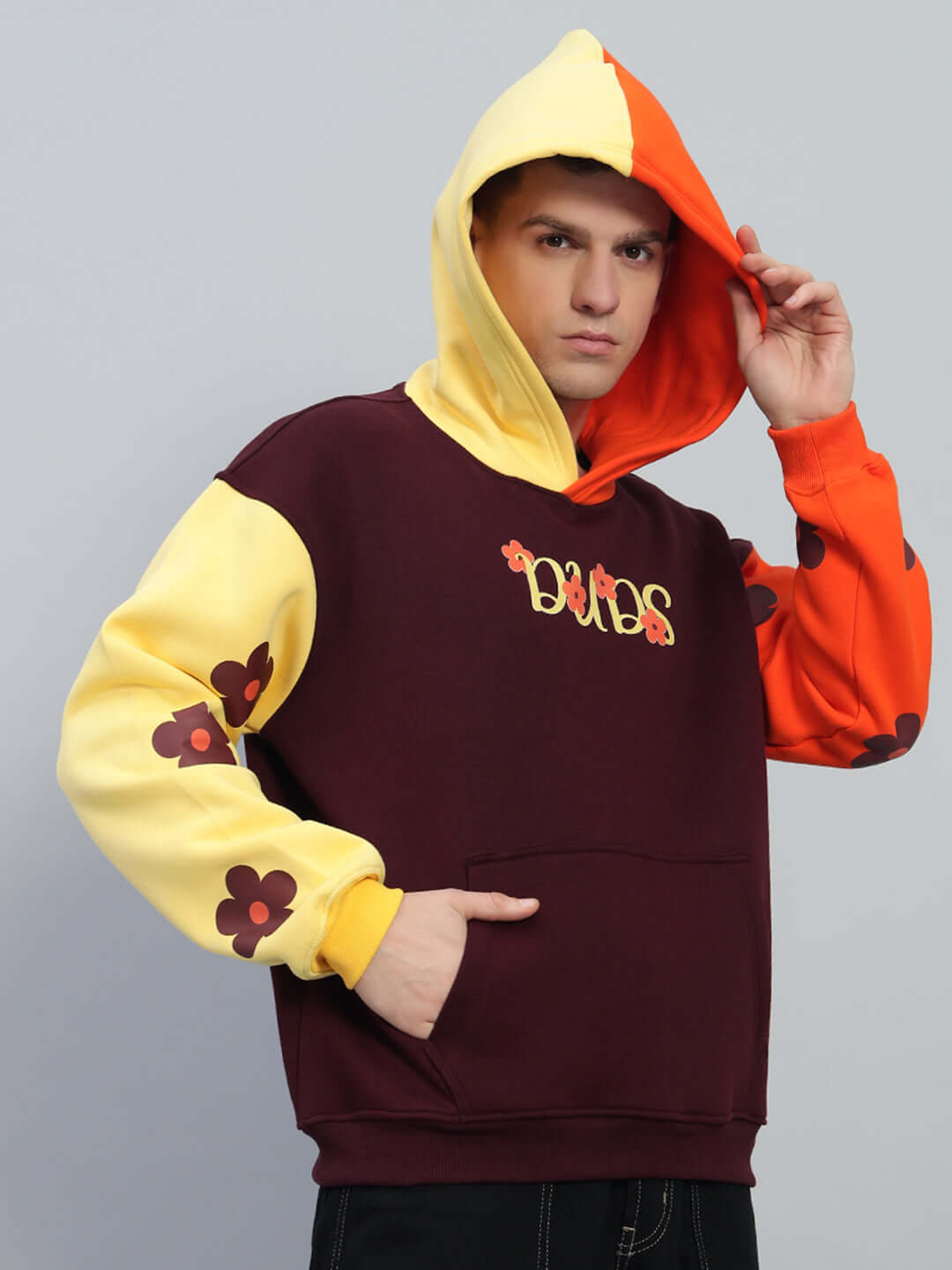 Model wearing COSMOS Oversized Fleece Hoodie in multi-color with floral design, featuring colorful hood and vibrant sleeves.