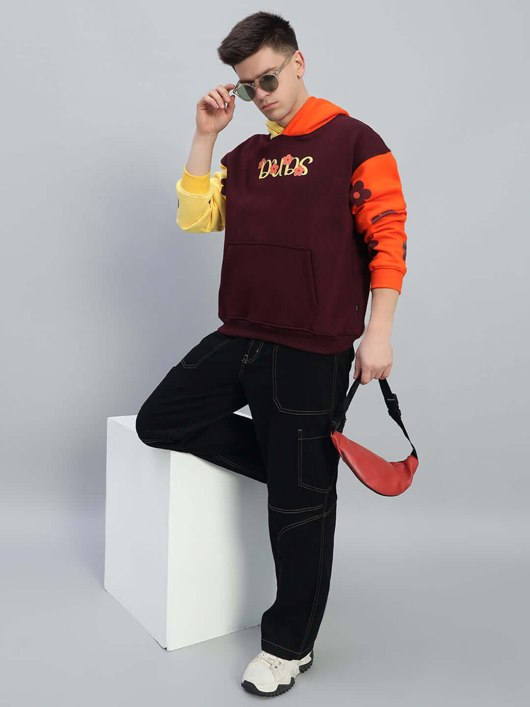 Model wearing Cosmos Oversized Fleece Hoodie in vibrant multi-color with cosmic graphics, paired with black pants and white sneakers.