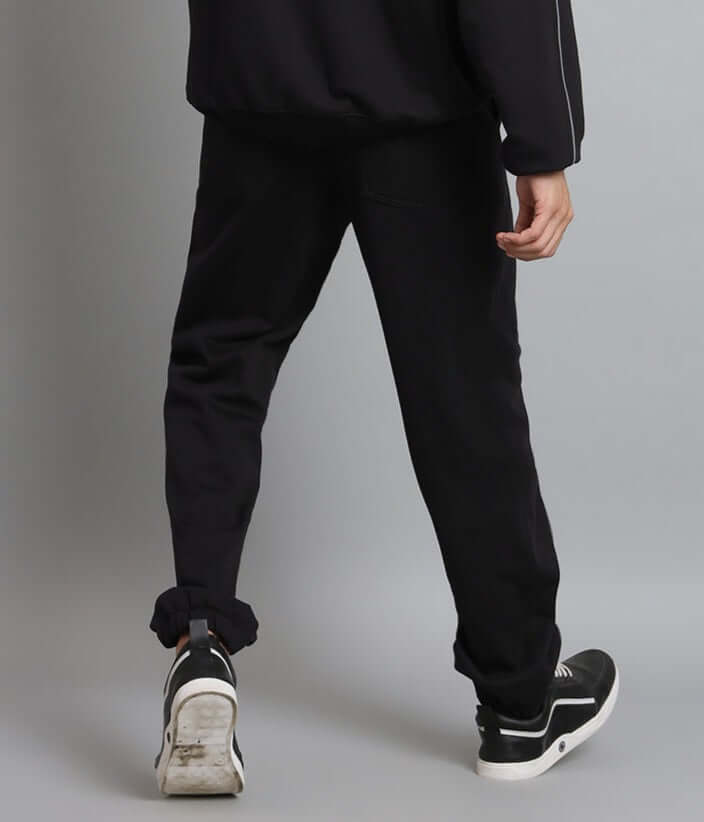 Back view of black ARMOR REFLECTOR fleece jogger pants being worn with black sneakers showcasing casual athletic style.