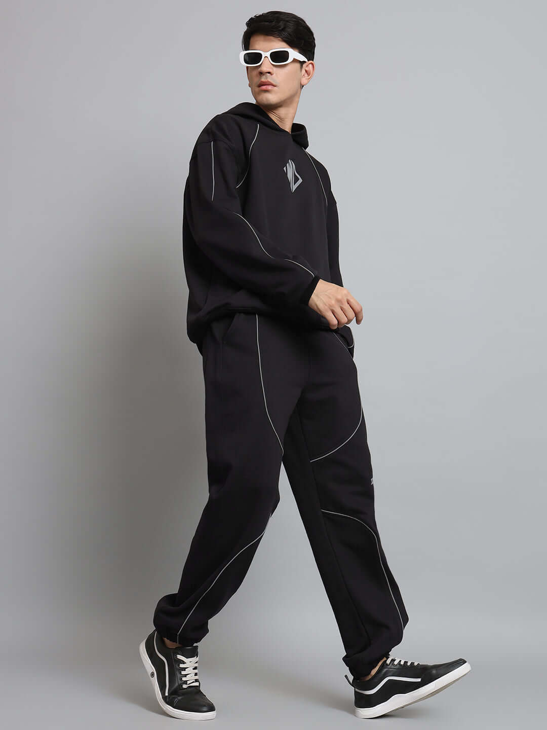 Model wearing Armor Reflector Fleece Jogger Black with white sneakers and sunglasses, showcasing urban street style fashion.