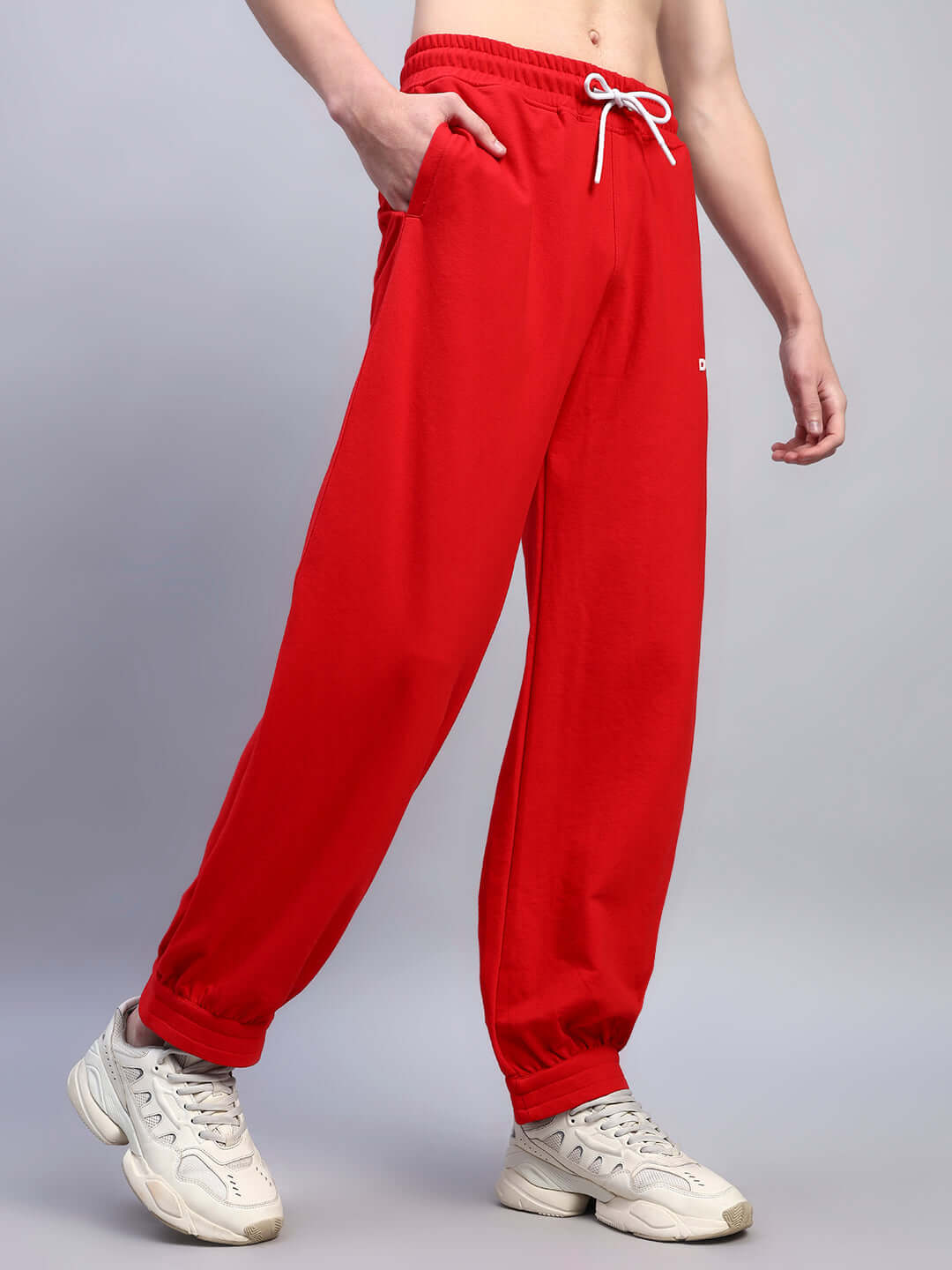Individual wearing Austrian relaxed-fit joggers in red, showcasing comfortable style with elastic waistband and white sneakers.