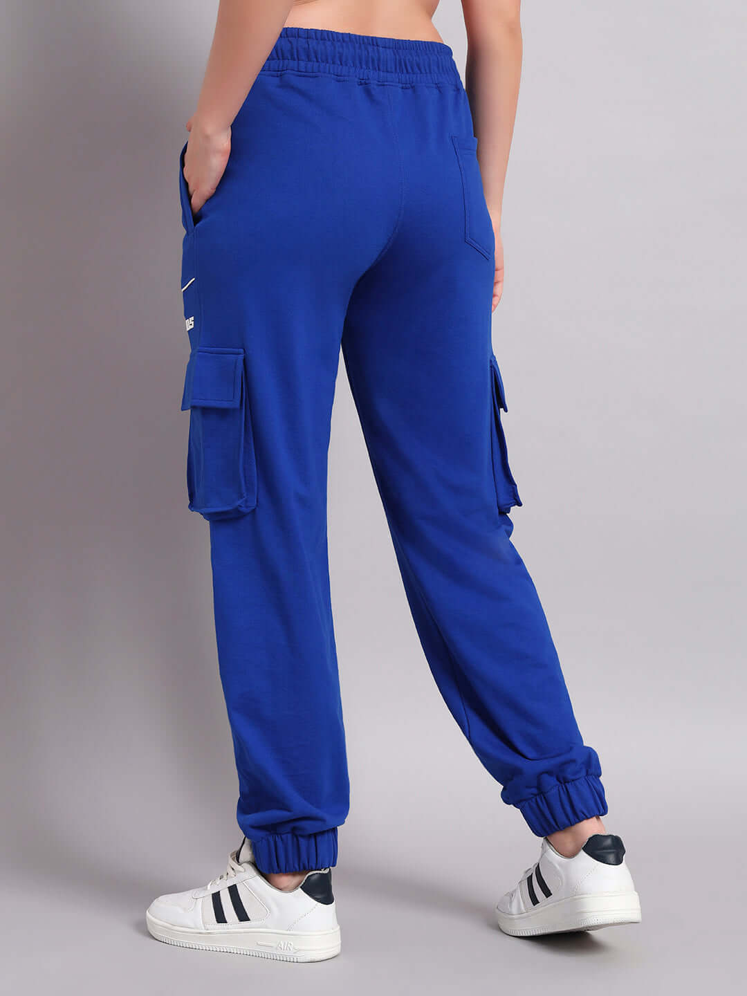 Back view of Women's Devano Relaxed-Fit Joggers in blue, showcasing elastic waist and cuffed ankles, paired with white sneakers.