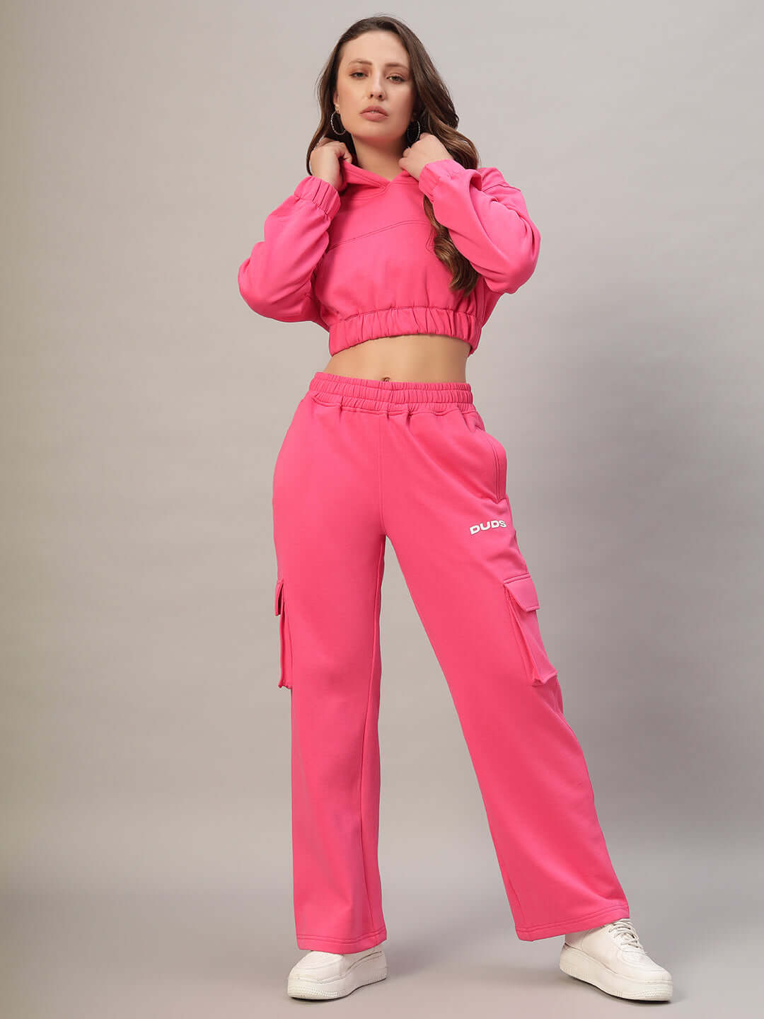 Woman wearing pink colorblock fleece co-ord set, featuring a cropped hoodie and cargo pants, styled with white sneakers.
