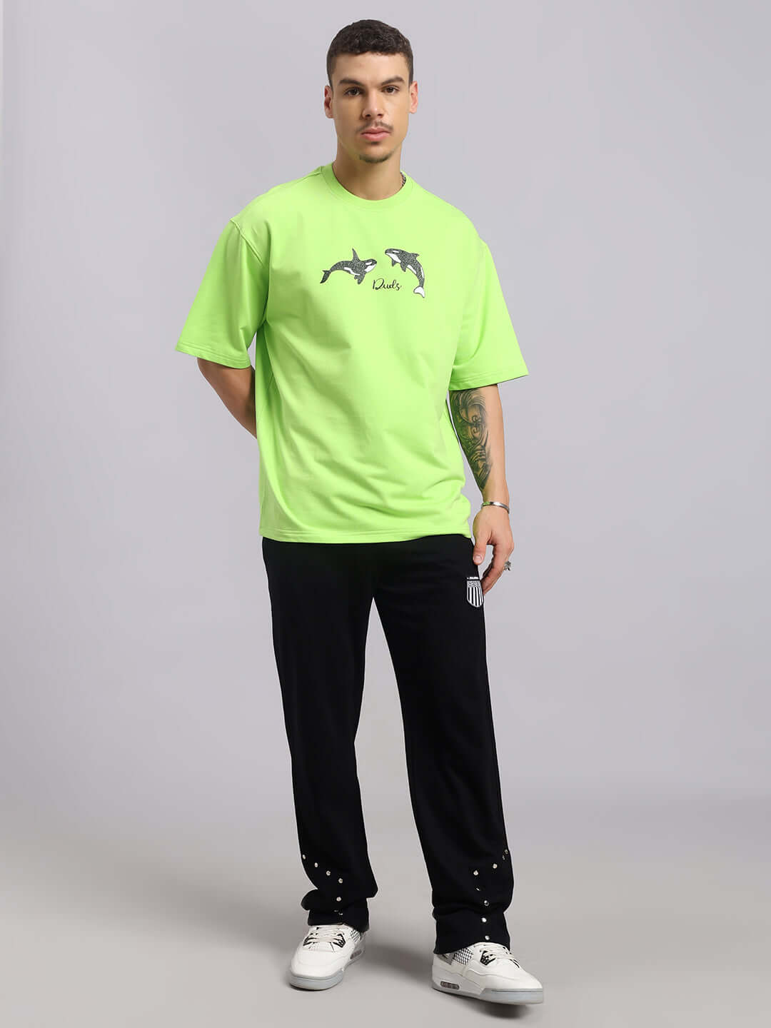 Man wearing neon green over-sized t-shirt with Orcas design, made from premium cotton French Terry, styled with black pants.