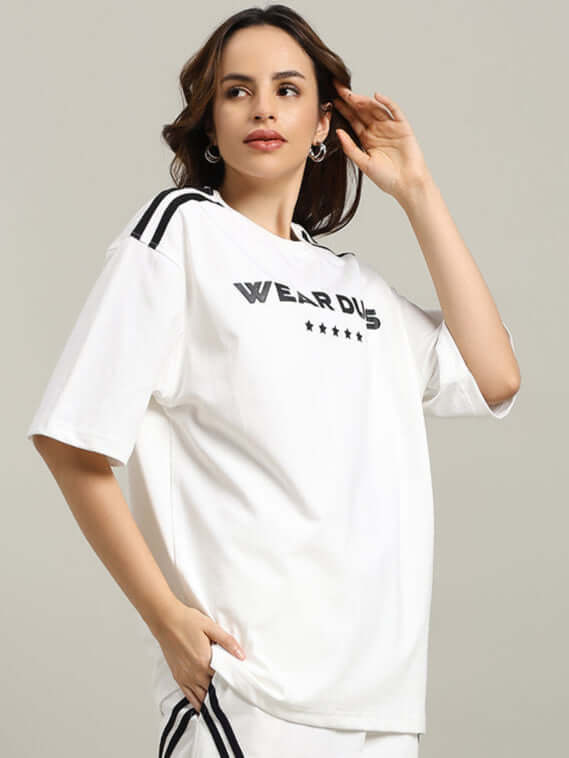 Model wearing women's oversized star jumper t-shirt in off white, featuring black stripes and text design, crafted from premium cotton fabric.