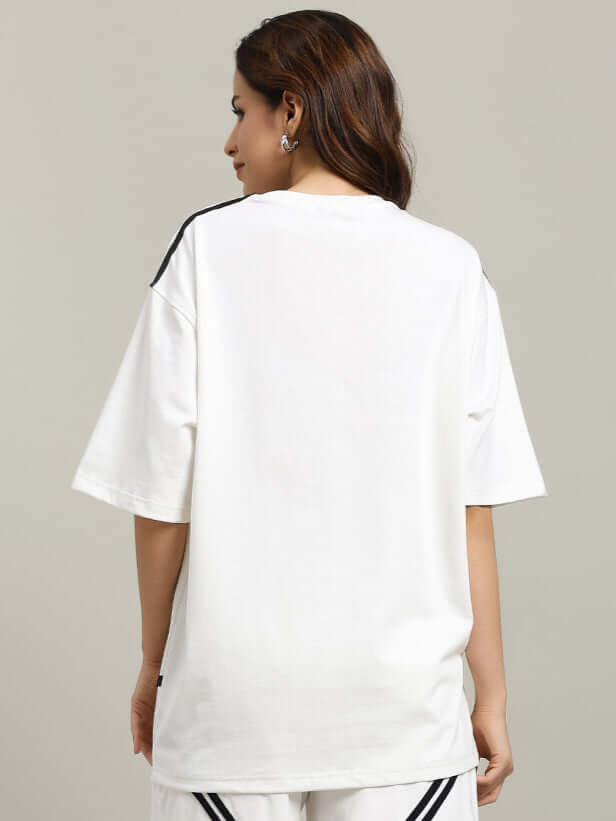 Woman wearing an oversized women's jumper t-shirt in off-white, made from premium cotton blend, featuring a star design. Back view.