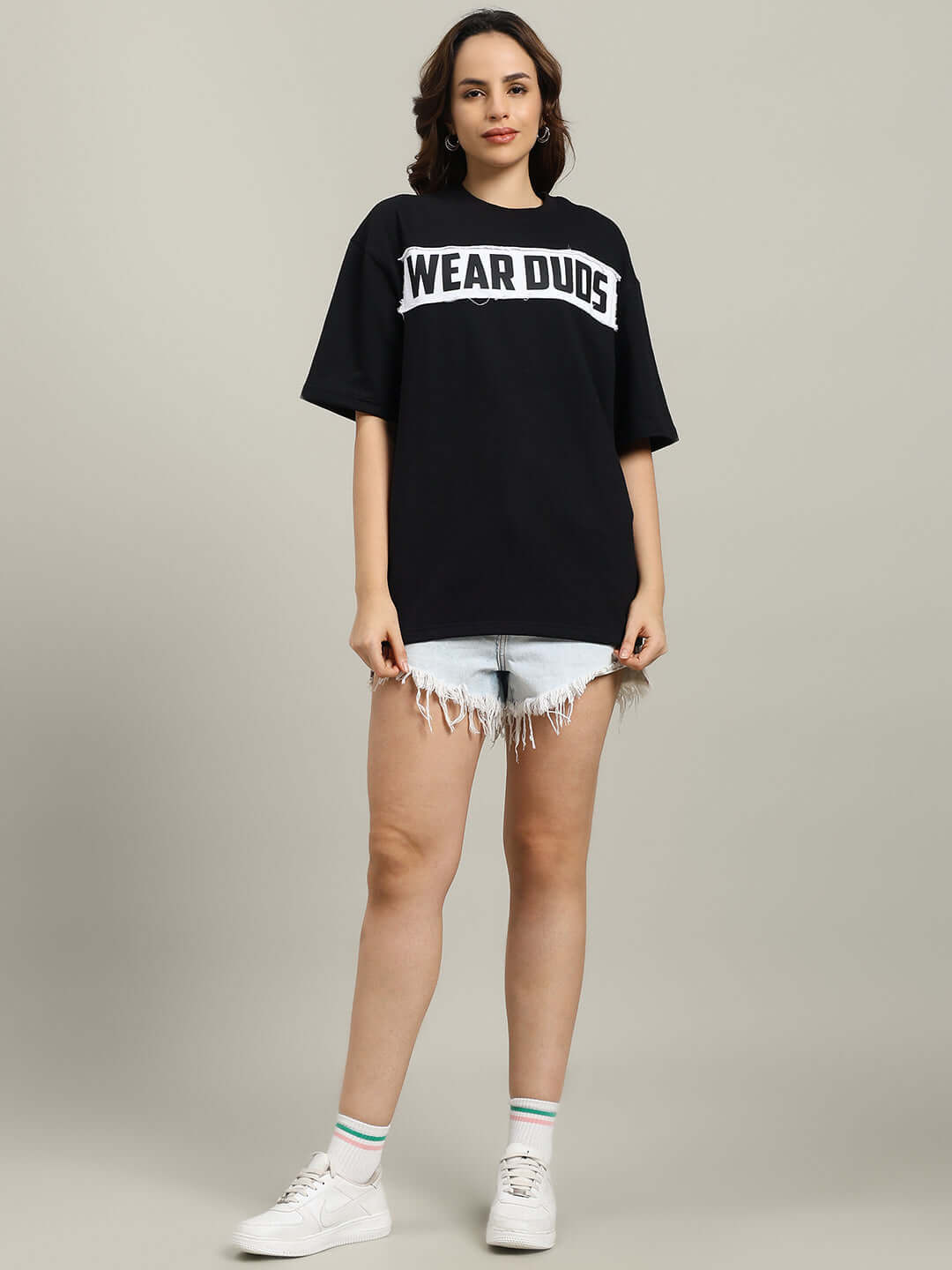 Black oversized women's Harley designer T-shirt made from premium cotton French terry, styled casually with denim shorts and sneakers.