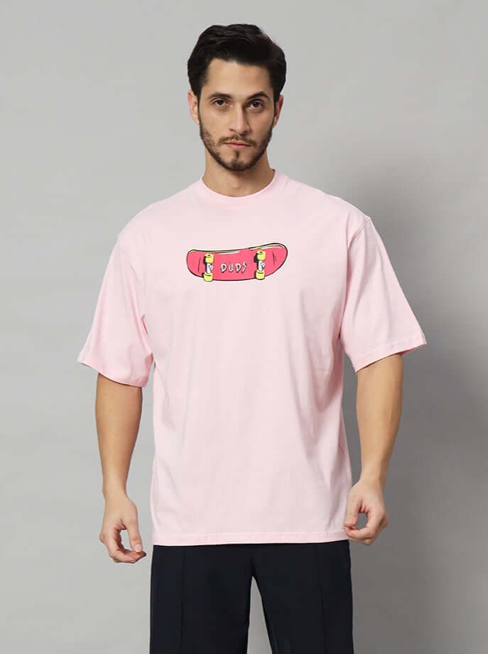 Person wearing ROWDY APE OVER-SIZED T-SHIRT PINK, featuring DUDS skateboard graphic.