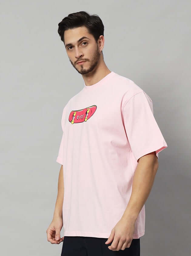 Man wearing a pink ROWDY APE OVER-SIZED T-SHIRT with skateboard graphic.