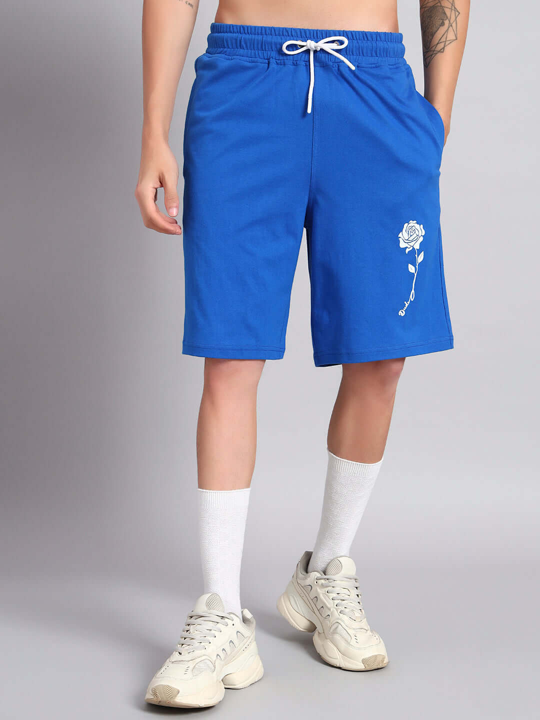 Model wearing blue LIMBO CO-ORD shorts with rose embroidery, crafted from 100% bio-washed cotton, displaying premium fashion style.