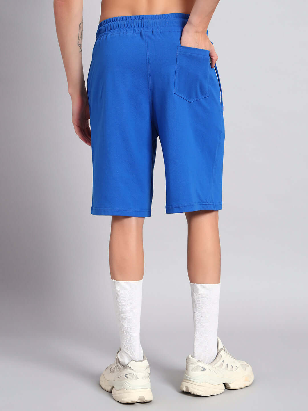Back view of blue LIMBO co-ord shorts in premium cotton fabric, showcasing pocket detail and elastic waist, worn with white socks and sneakers.