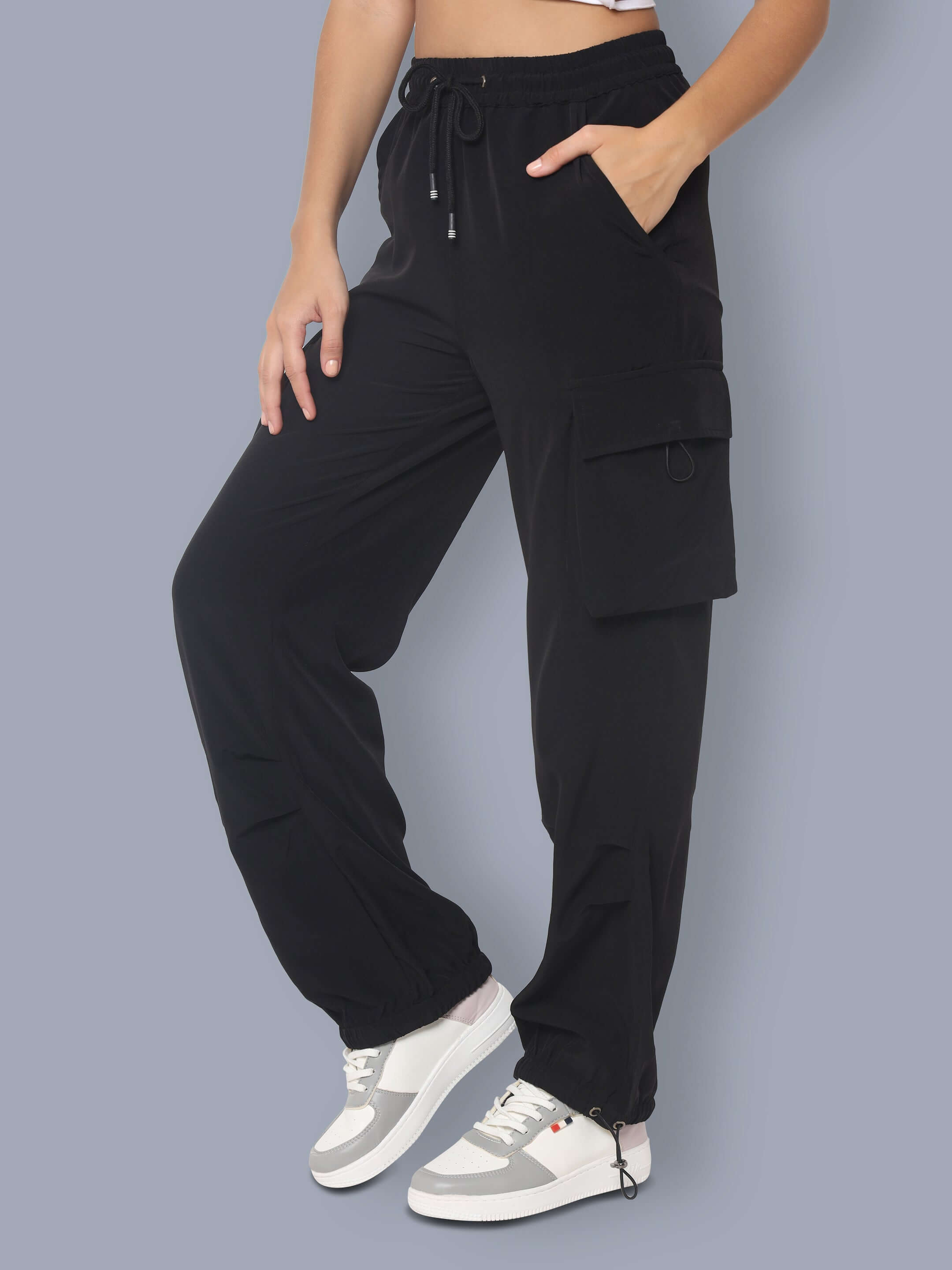 Women's black tactical cargo joggers with pockets, shown with white sneakers.
