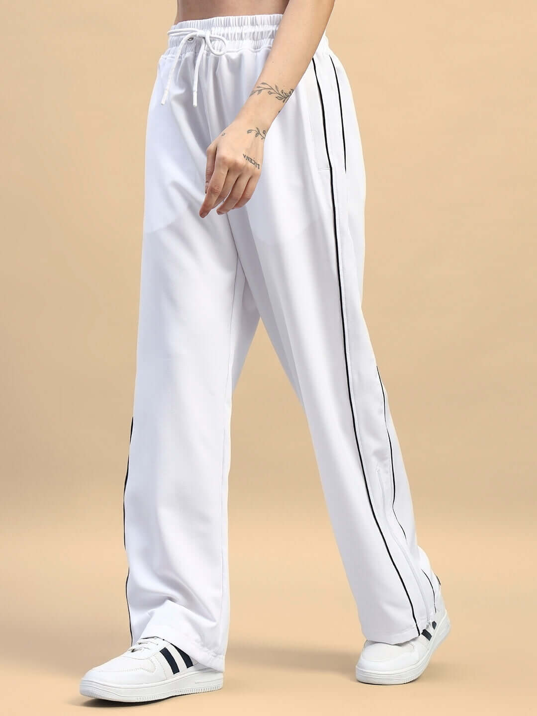 Woman wearing white relaxed-fit joggers with side stripes, showcasing casual comfort and style for everyday wear.