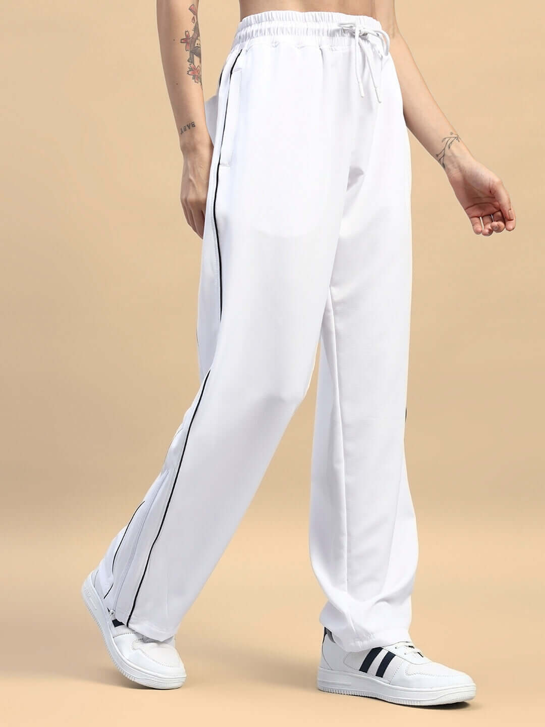 Women's white relaxed-fit joggers with drawstring waist, side stripes, and sneakers. Ideal for casual or athletic wear.