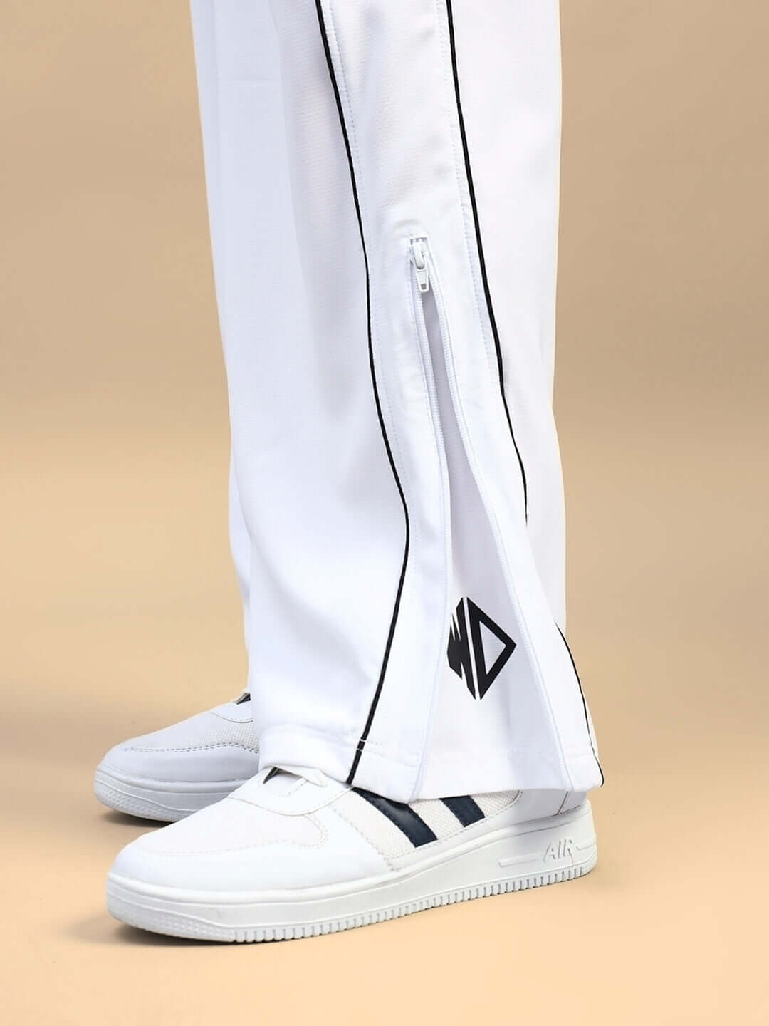 Close-up of women's white relaxed-fit joggers with zip details and black accents, paired with white sneakers.