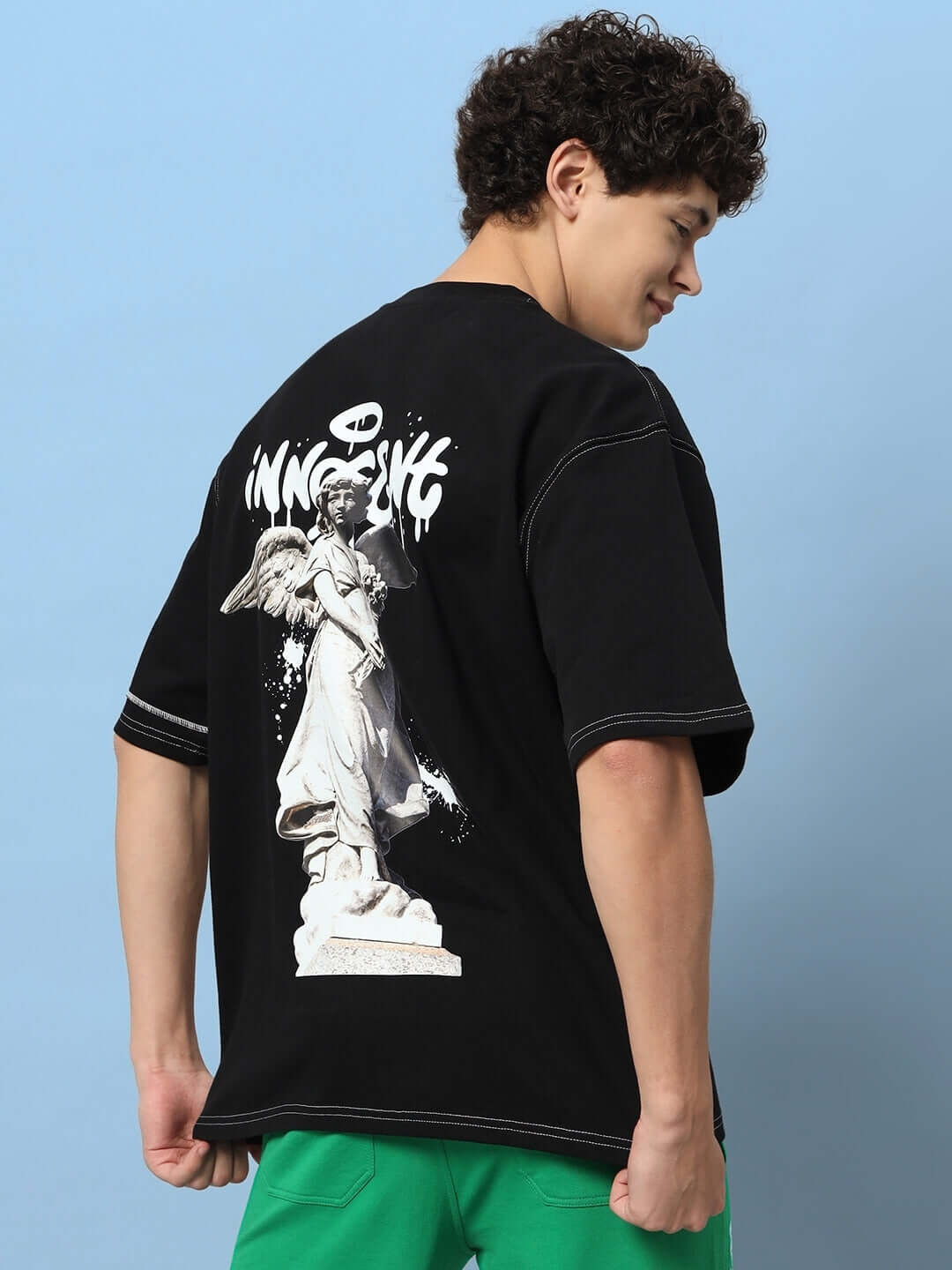 INNOCENT CONTRAST STITCHED OVER-SIZED T-SHIRT BLACK with unique graphic design, made from premium heavy gauge fabric, worn by a model.
