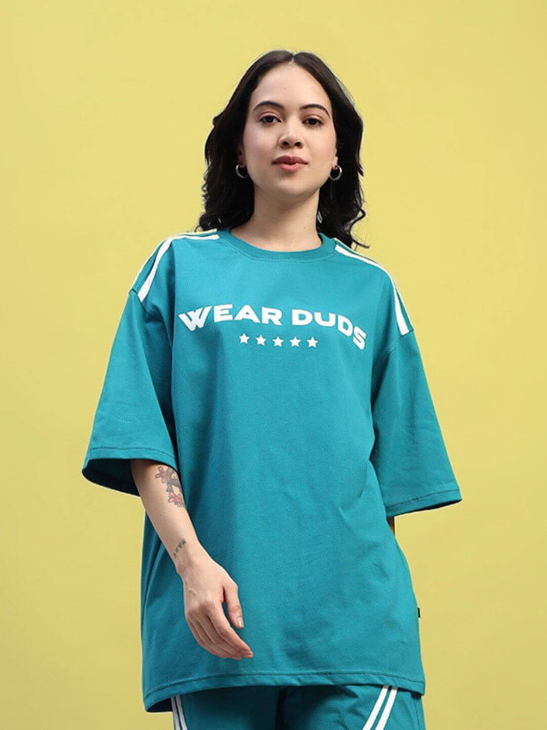 Woman wearing teal oversized t-shirt with 'Wear Duds' print against yellow background