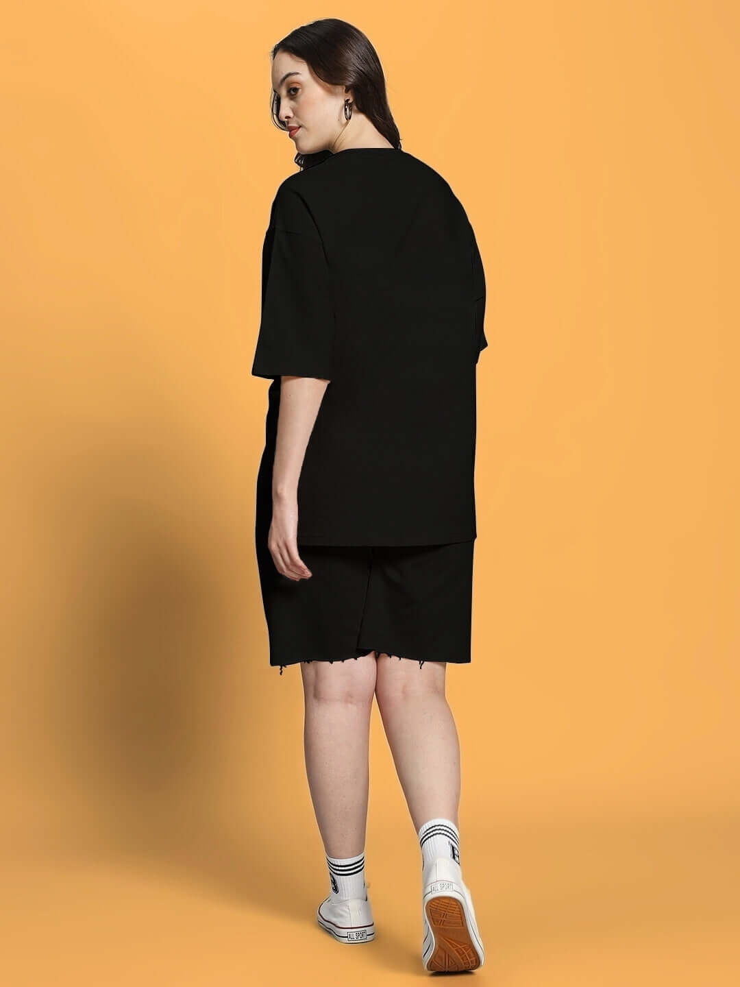 Back view of woman wearing Women's Fancy Dream Co-ord Set in black, made from premium cotton French terry lycra, standing on orange background.