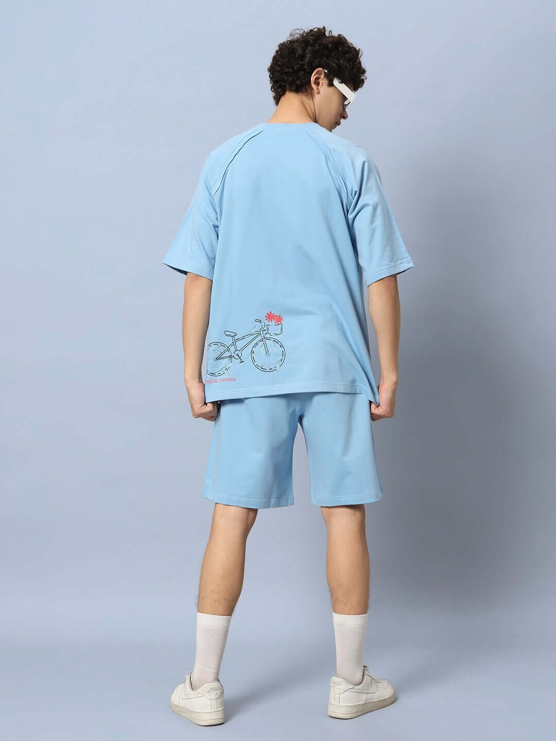 Back view of man wearing ENJOY THE RIDE PRINTED CO-ORD SET BLUE with bicycle design, 100% cotton fabric, casual summer look.