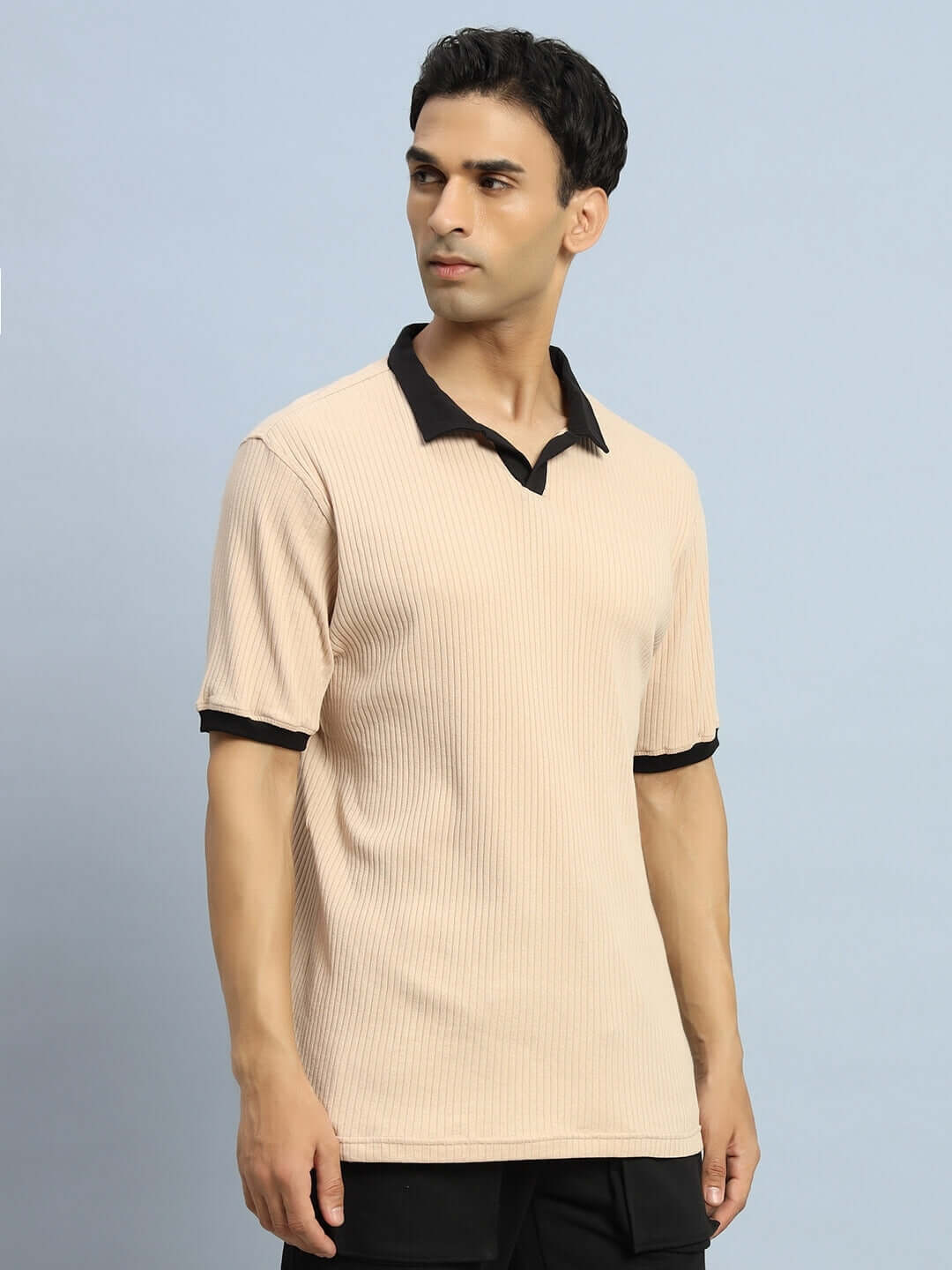 Man wearing FILIPINO REGULAR FIT T-SHIRT BEIGE with half sleeves and black collar, standing against light blue background.