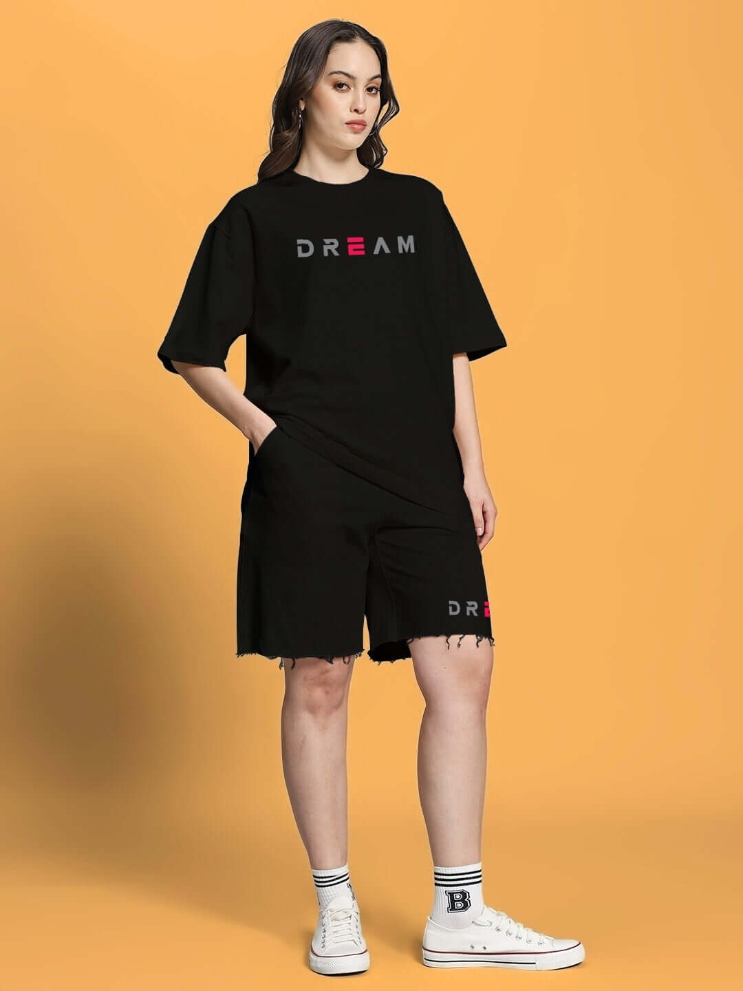 Woman wearing a women's fancy dream black co-ord set made from premium cotton French terry lycra, posing against an orange background.