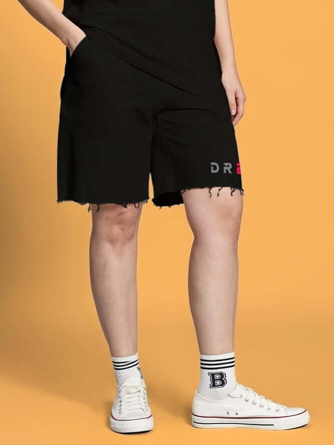 Woman wearing black regular fit shorts with customized fit option by DUDS, featuring embroidered logo, paired with white sneakers.
