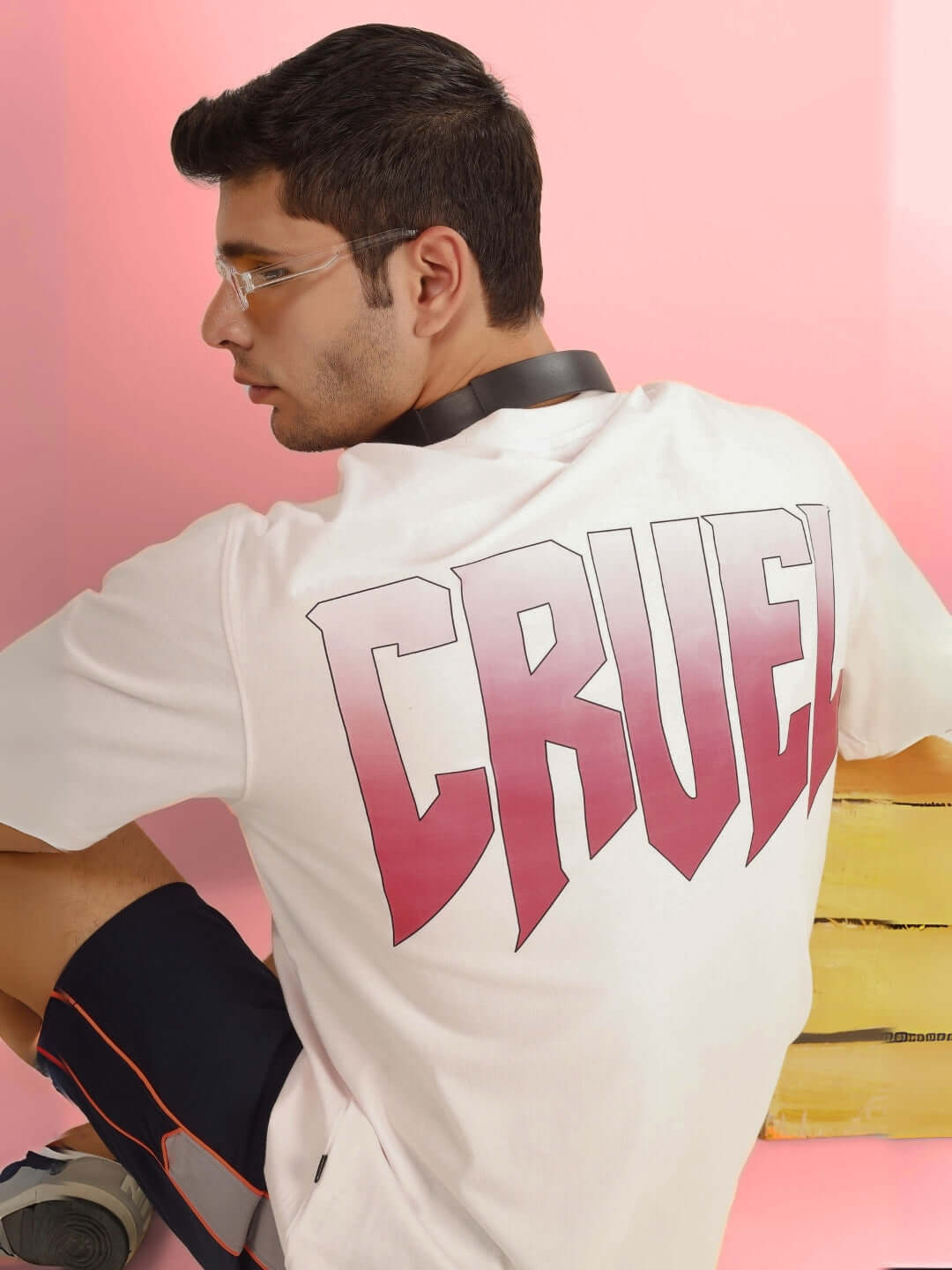 Model wearing CRUEL OVER-SIZED T-SHIRT BABY PINK with bold lettering on back.