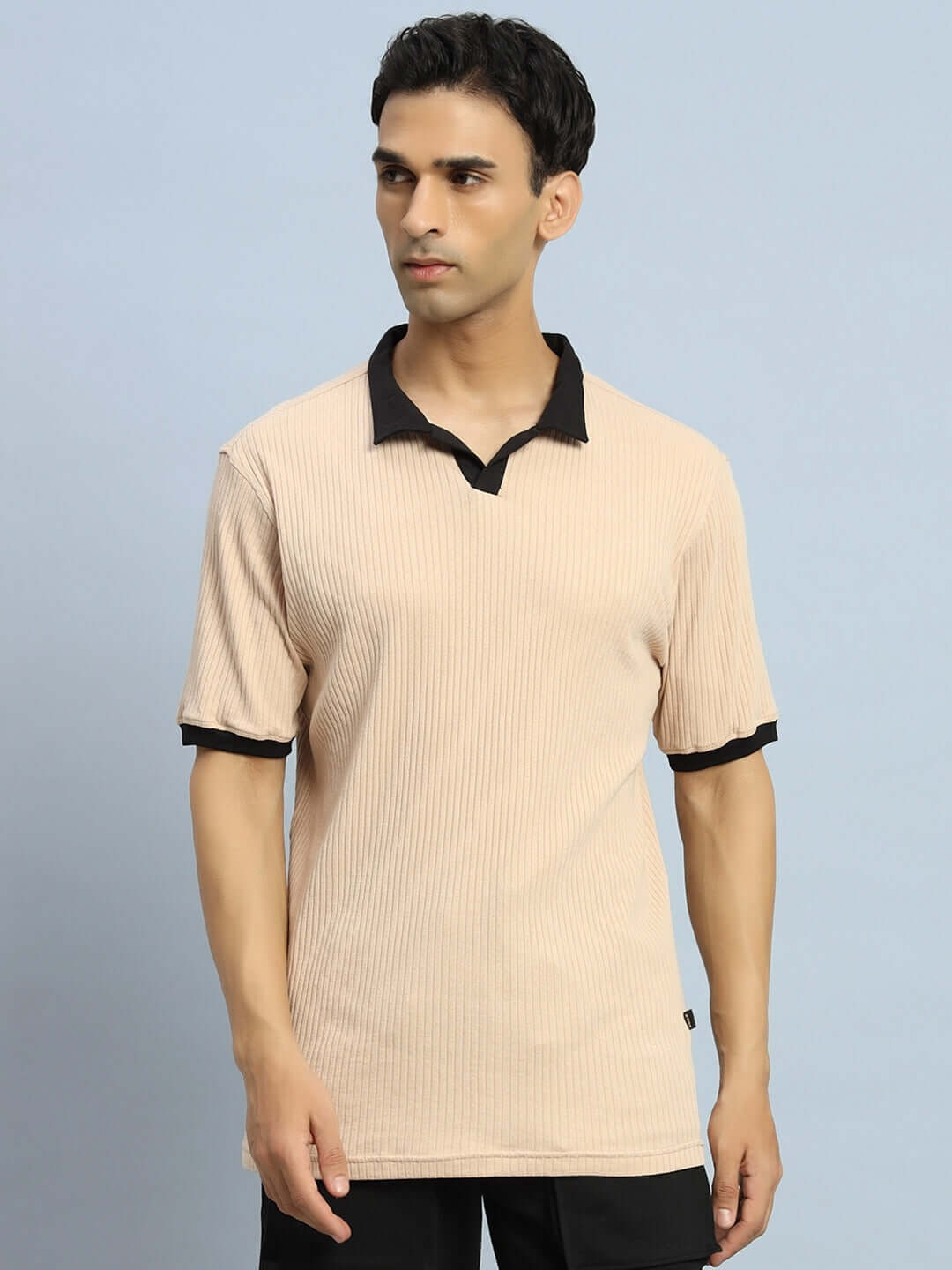 Man wearing FILIPINO REGULAR FIT T-SHIRT BEIGE with half sleeves and black collar, standing against blue background.