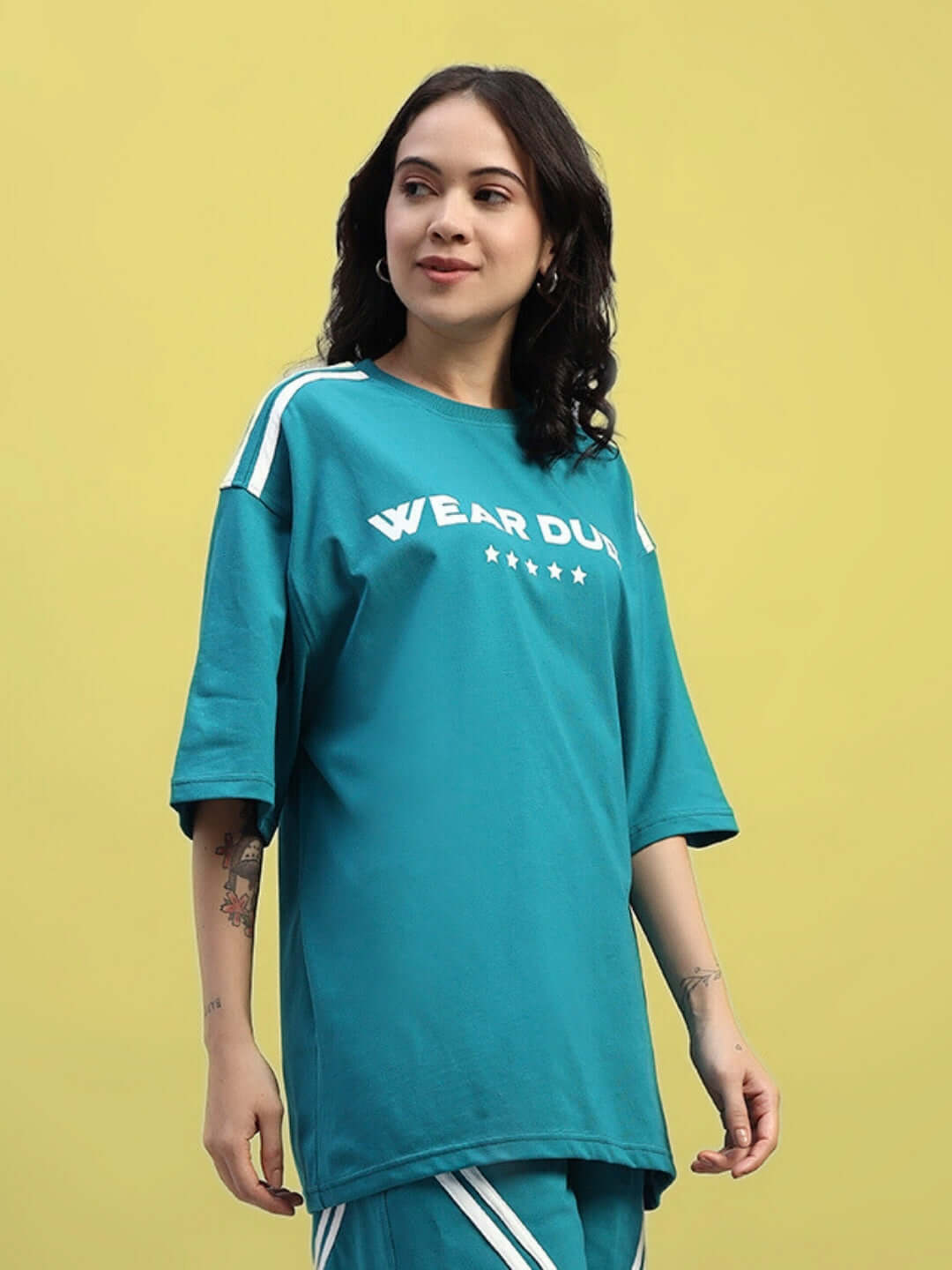 Woman wearing teal oversized t-shirt "Star Jumper" made from premium cotton blend, featuring stripes on sleeves.