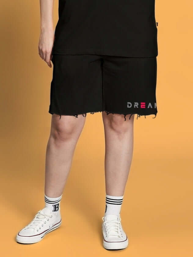 Women's Fancy Dream Regular Fit Black Shorts with custom fit option, featuring a stylish frayed hem and logo detail, worn with white sneakers.