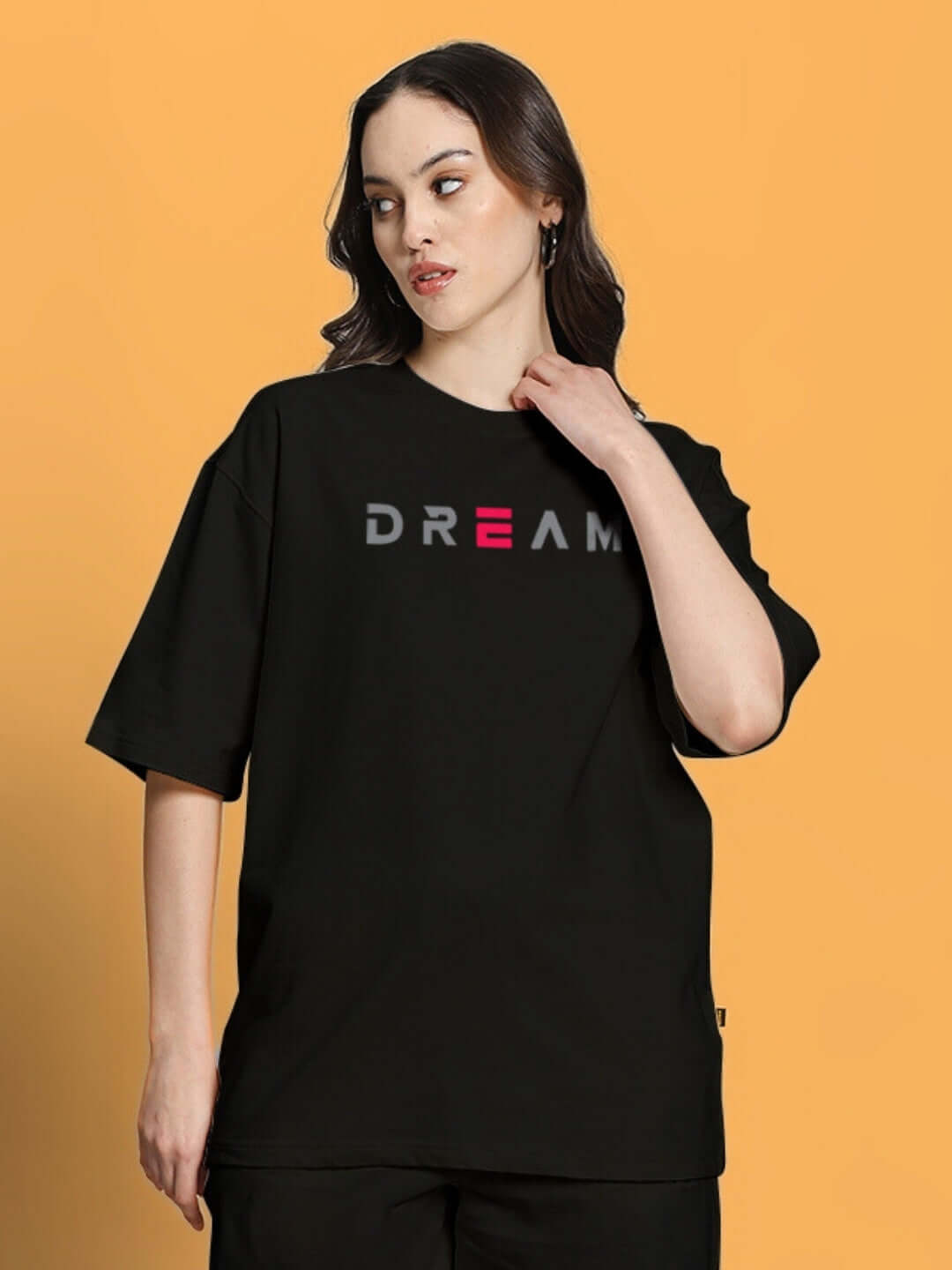 Woman wearing black oversized "Dream" T-shirt made of premium cotton and elastane blend, ideal for casual stylish wear.