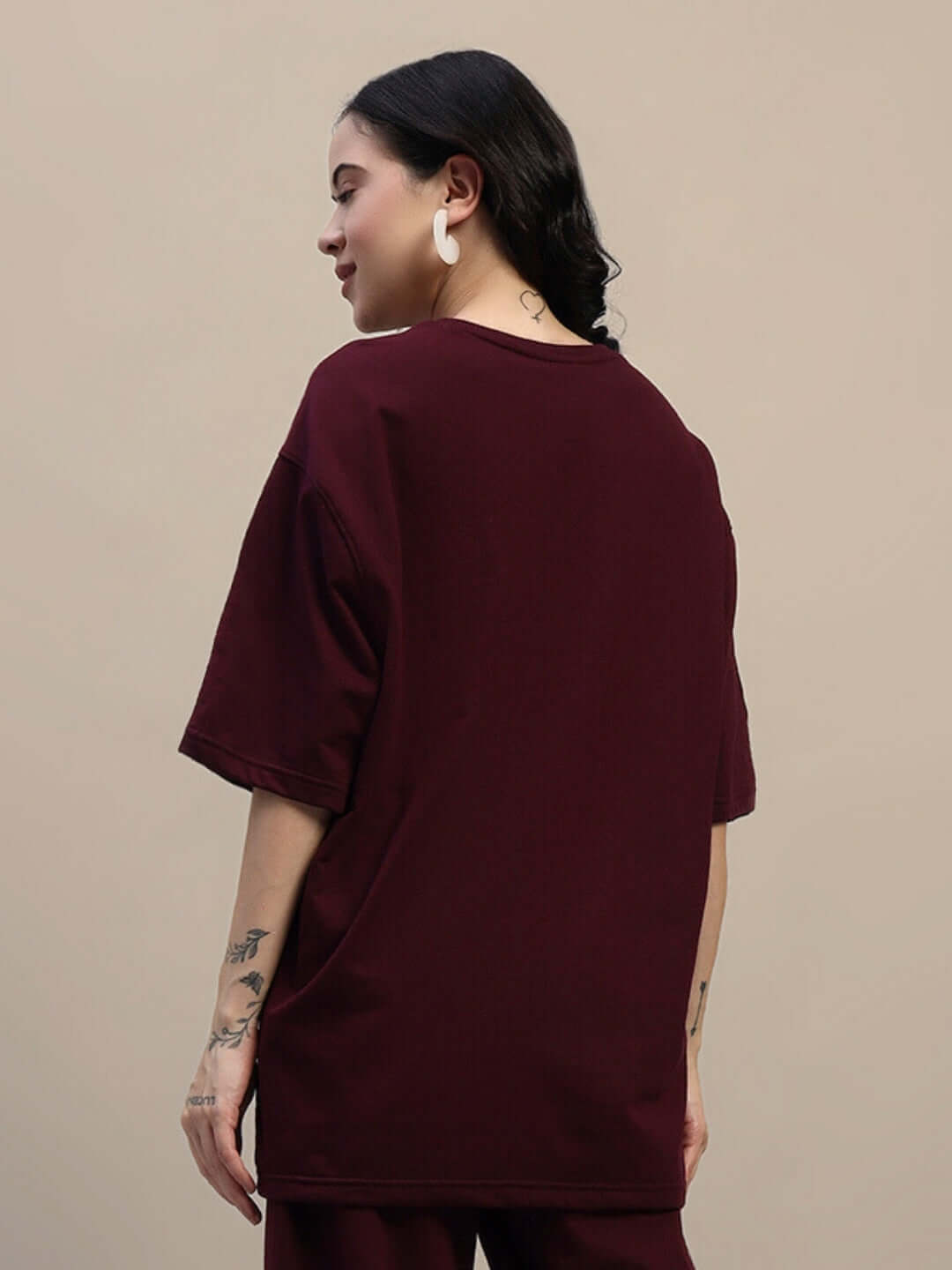 Back view of a woman wearing a maroon oversized T-shirt, highlighting the premium fabric and relaxed fit. Perfect for casual wear.