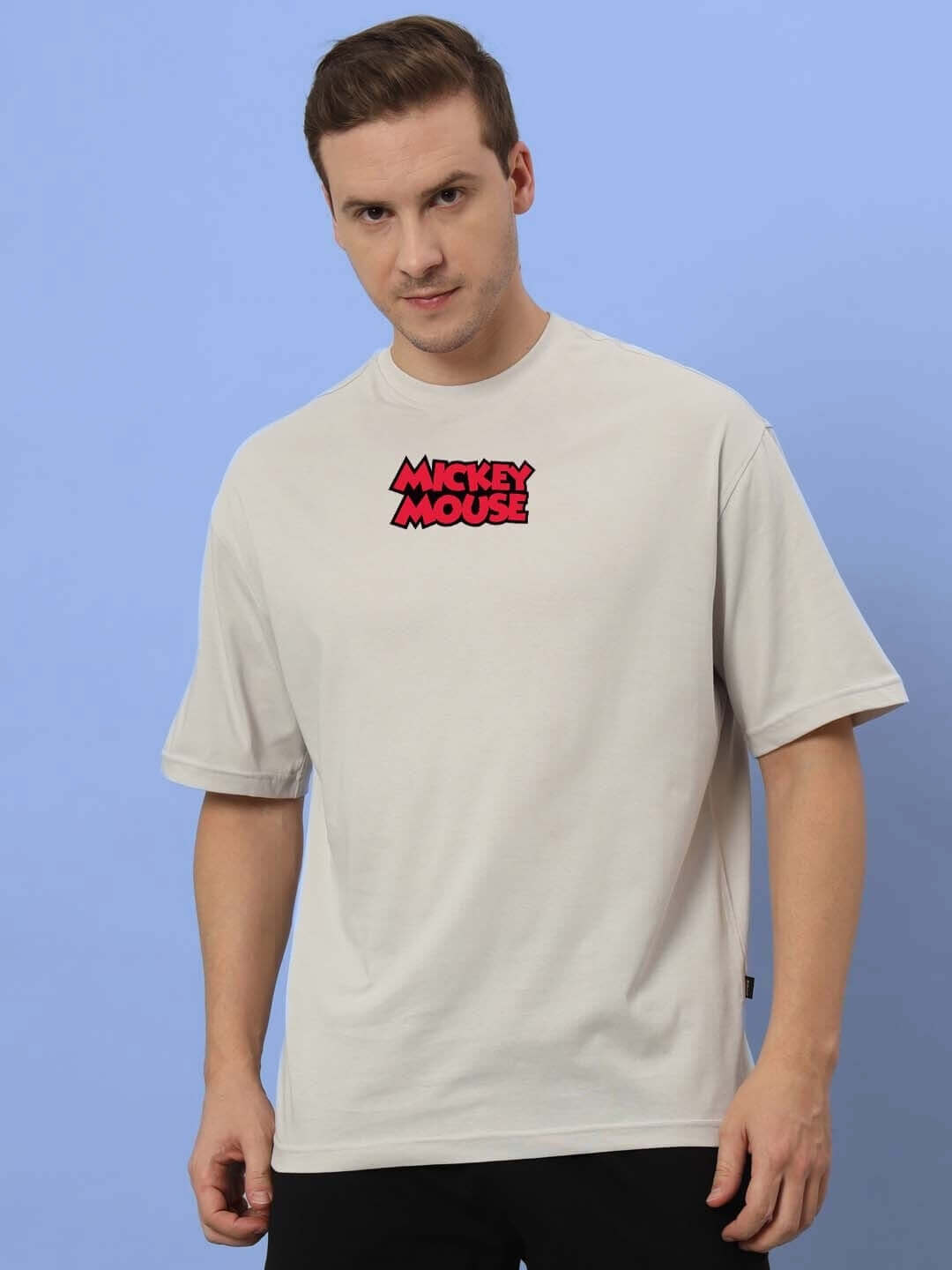 Man wearing DUDS MOUSE OVER-SIZED T-SHIRT GREY with Mickey Mouse logo on a light blue background.