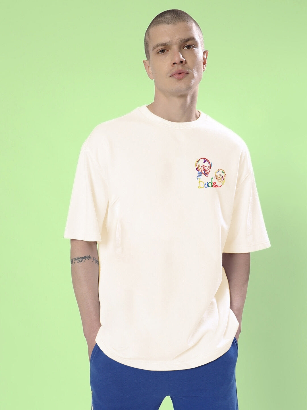 Model wearing SKULL ROLL OVERSIZED T-SHIRT OFF WHITE, featuring skull design on a light green background.