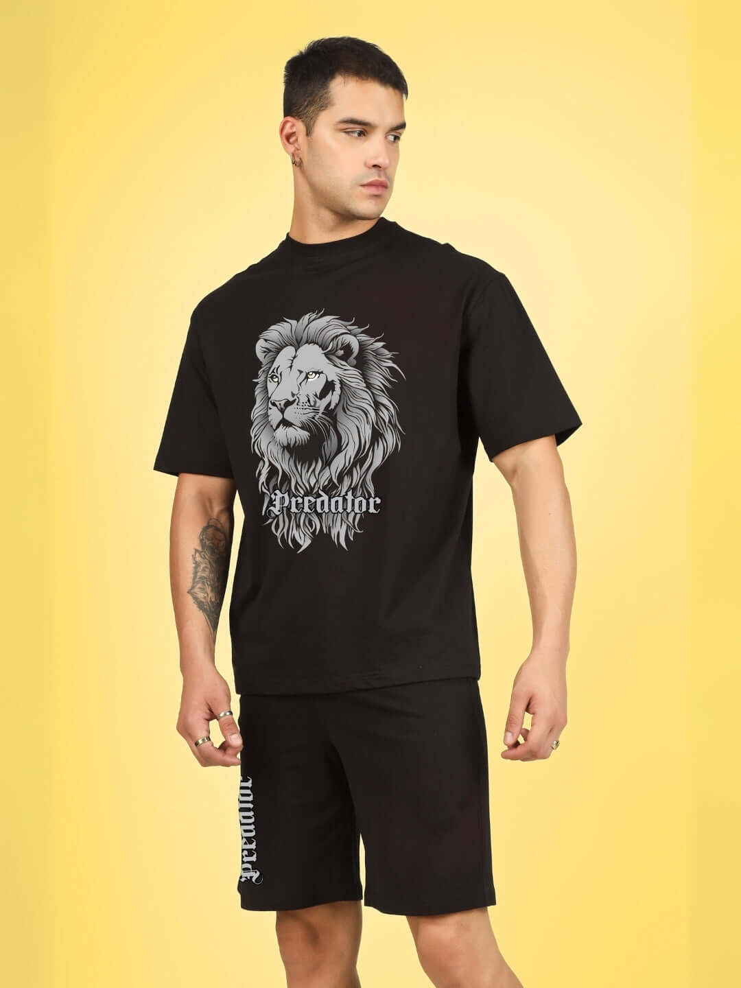 Model wearing Predator Legend black co-ord set with lion print, made of premium cotton French terry lycra, on yellow background.