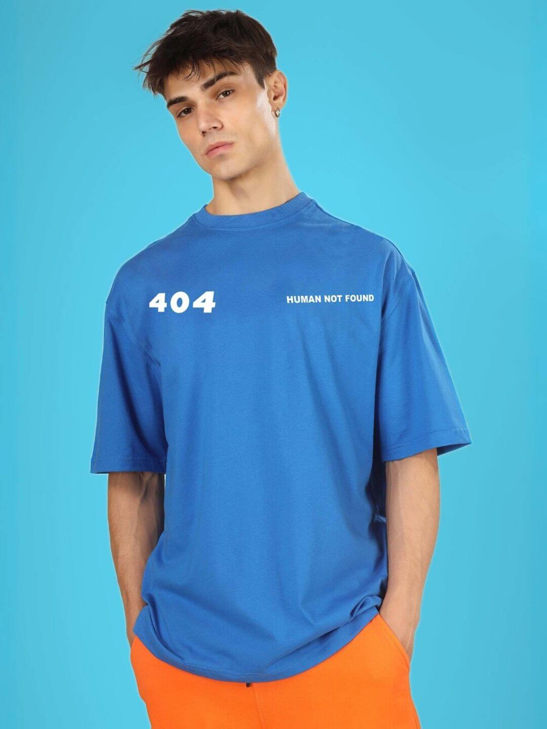 Man wearing 404 ERROR OVER-SIZED T-SHIRT ROYAL BLUE with tech-themed graphics