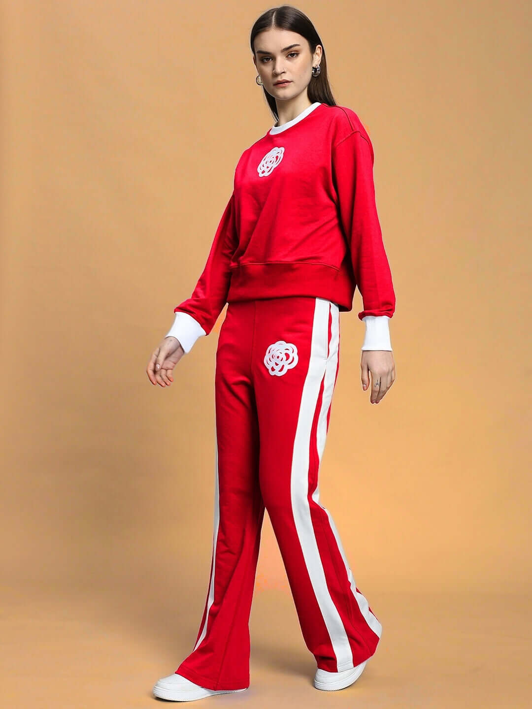Woman wearing a red relaxed fit co-ord set with white contrast panels, featuring elasticated waistband and floral emblem on chest and pants.