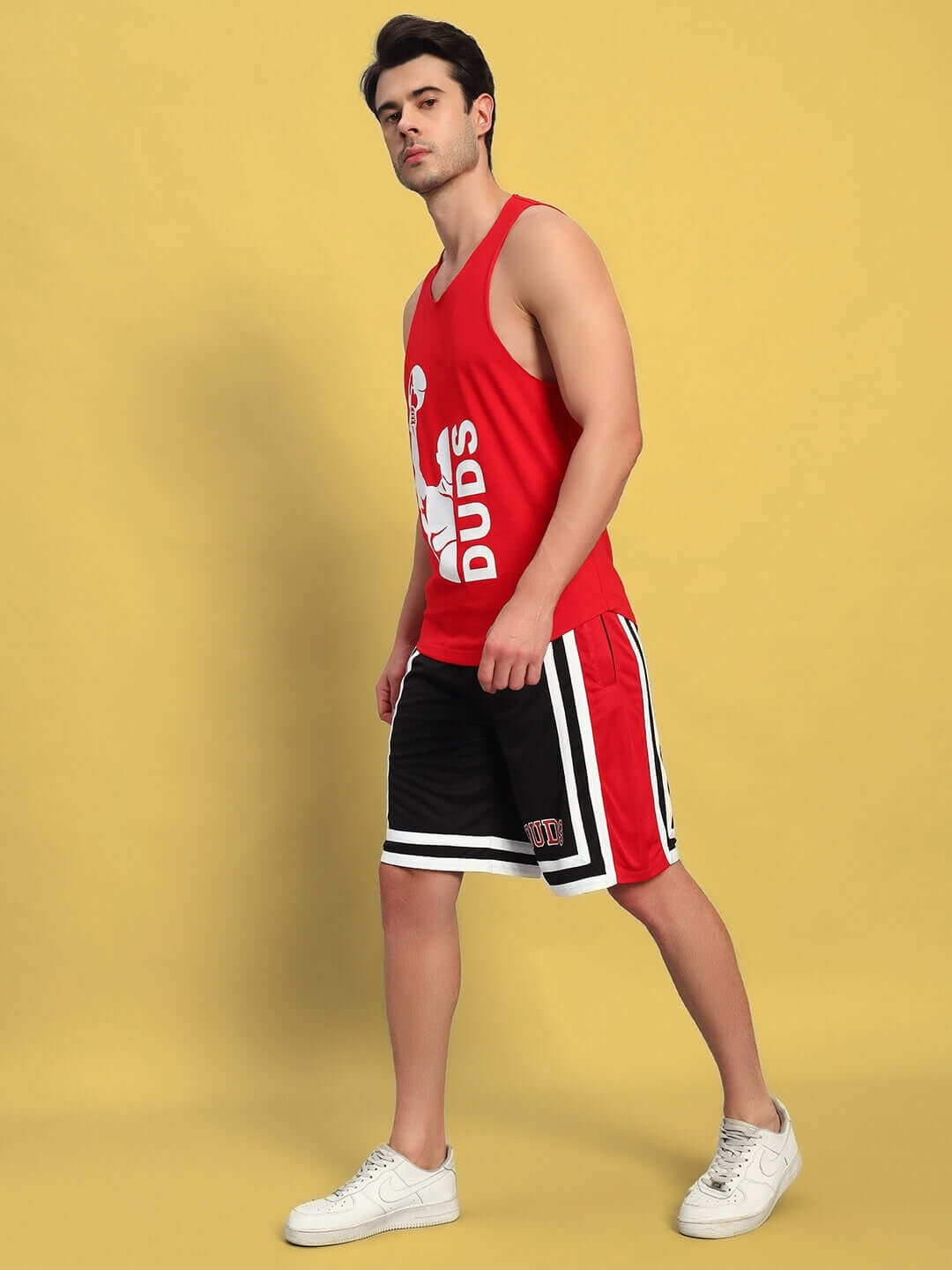 Model wearing MAX GYM CO-ORD SET in red and black, featuring a sleeveless vest and sports shorts against a yellow background.