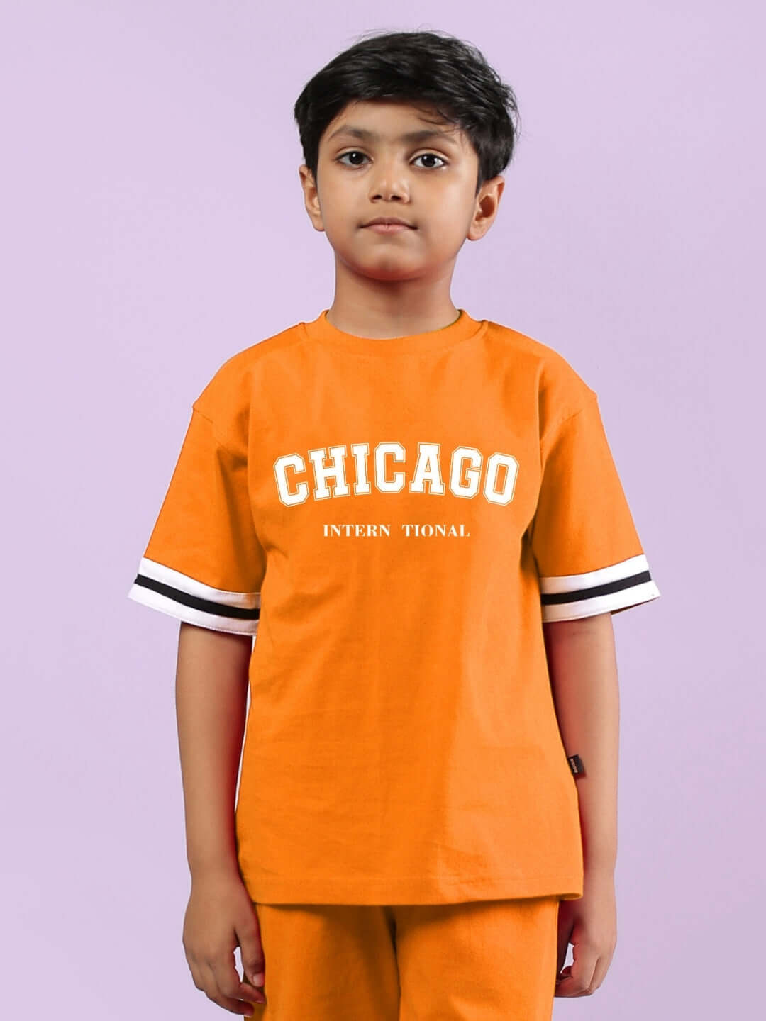 Child wearing orange Chicago printed T-shirt for boys and girls, featuring white text and striped sleeves.