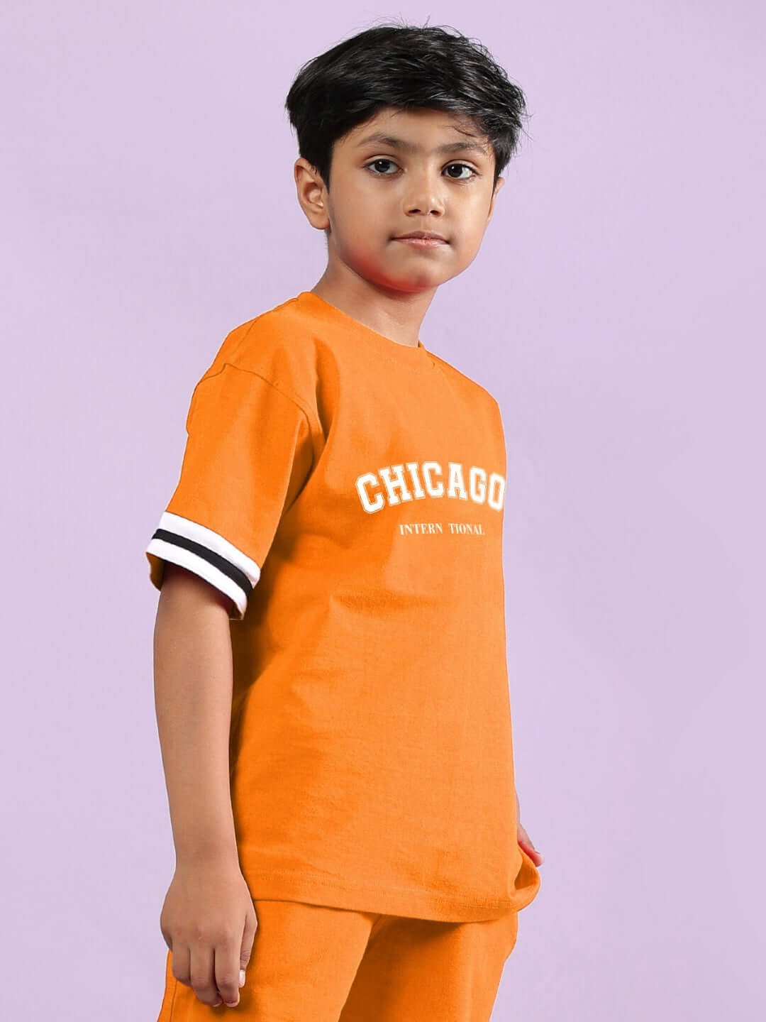 Child wearing orange Chicago printed t-shirt for boys and girls, showcasing casual style with white striped sleeves.