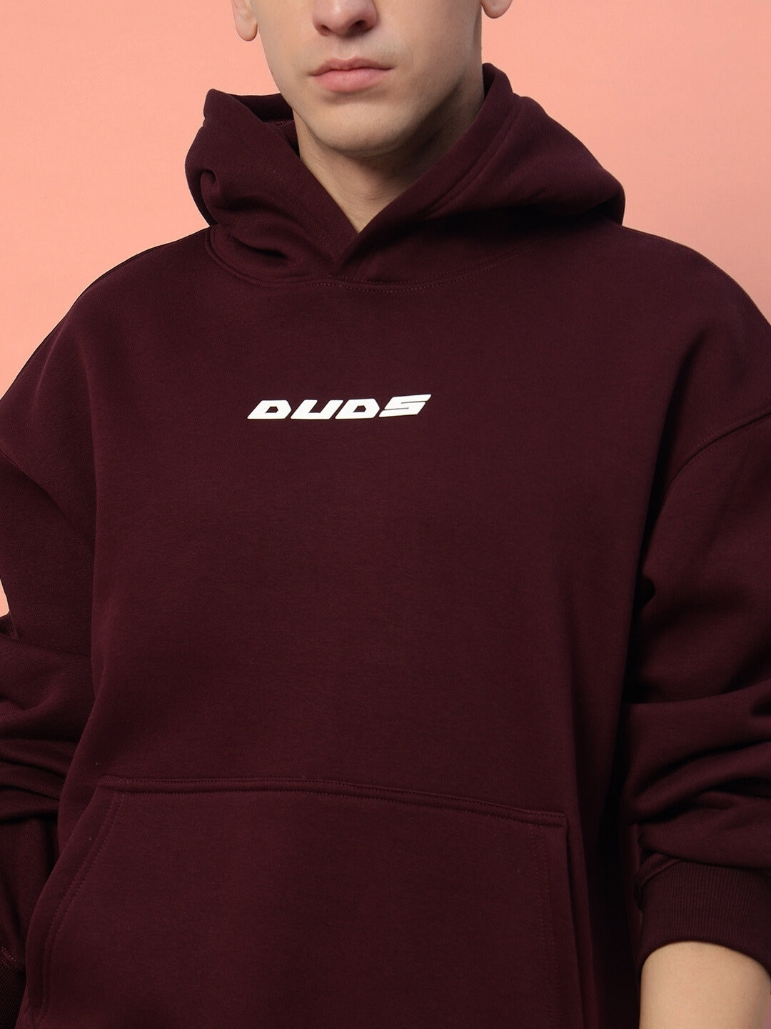 Person wearing a wine-colored fleece hoodie with 'DUDES' text, showcasing cozy and stylish fashion for comfort.