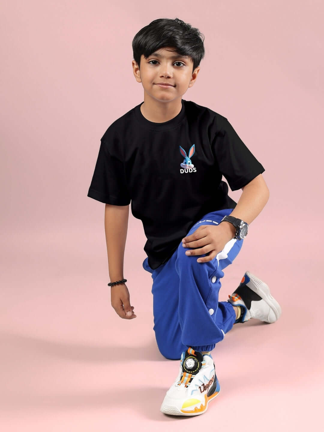 Boy wearing black Tiny Toon printed t-shirt and blue pants, showcasing casual kids' fashion from DUDS