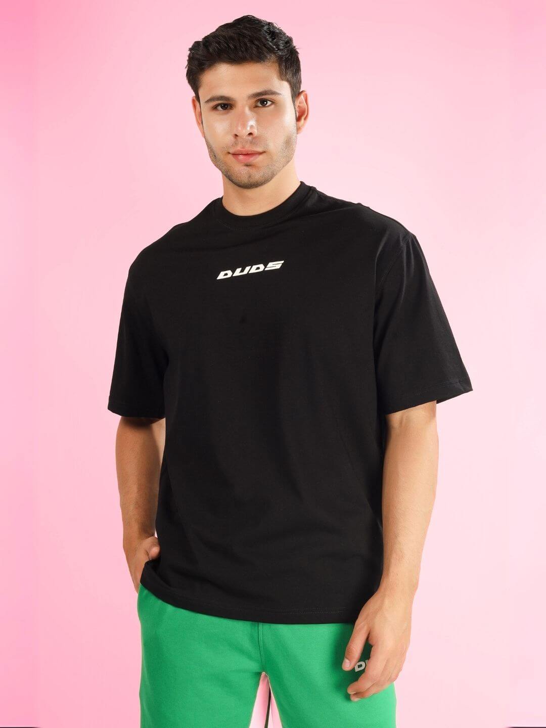 Model wearing ENJOY THE WIND OVER-SIZED T-SHIRT BLACK against a pink background