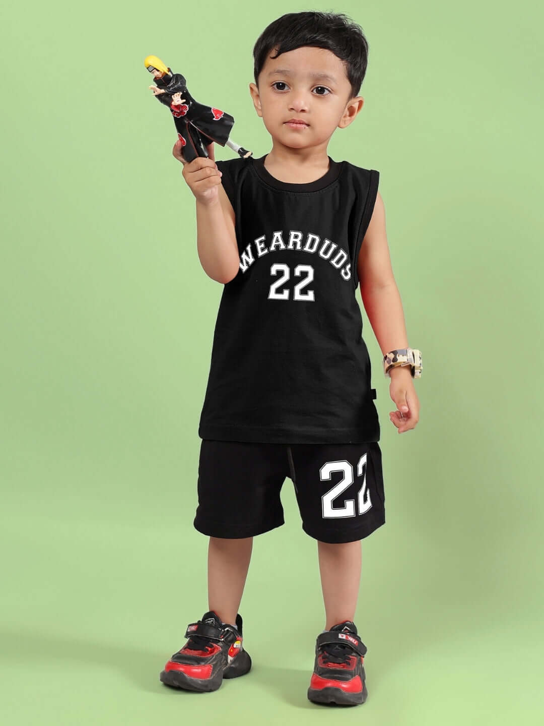 Child wearing AMIGA black co-ord set, featuring sleeveless shirt and shorts, holding a toy, customized options available.