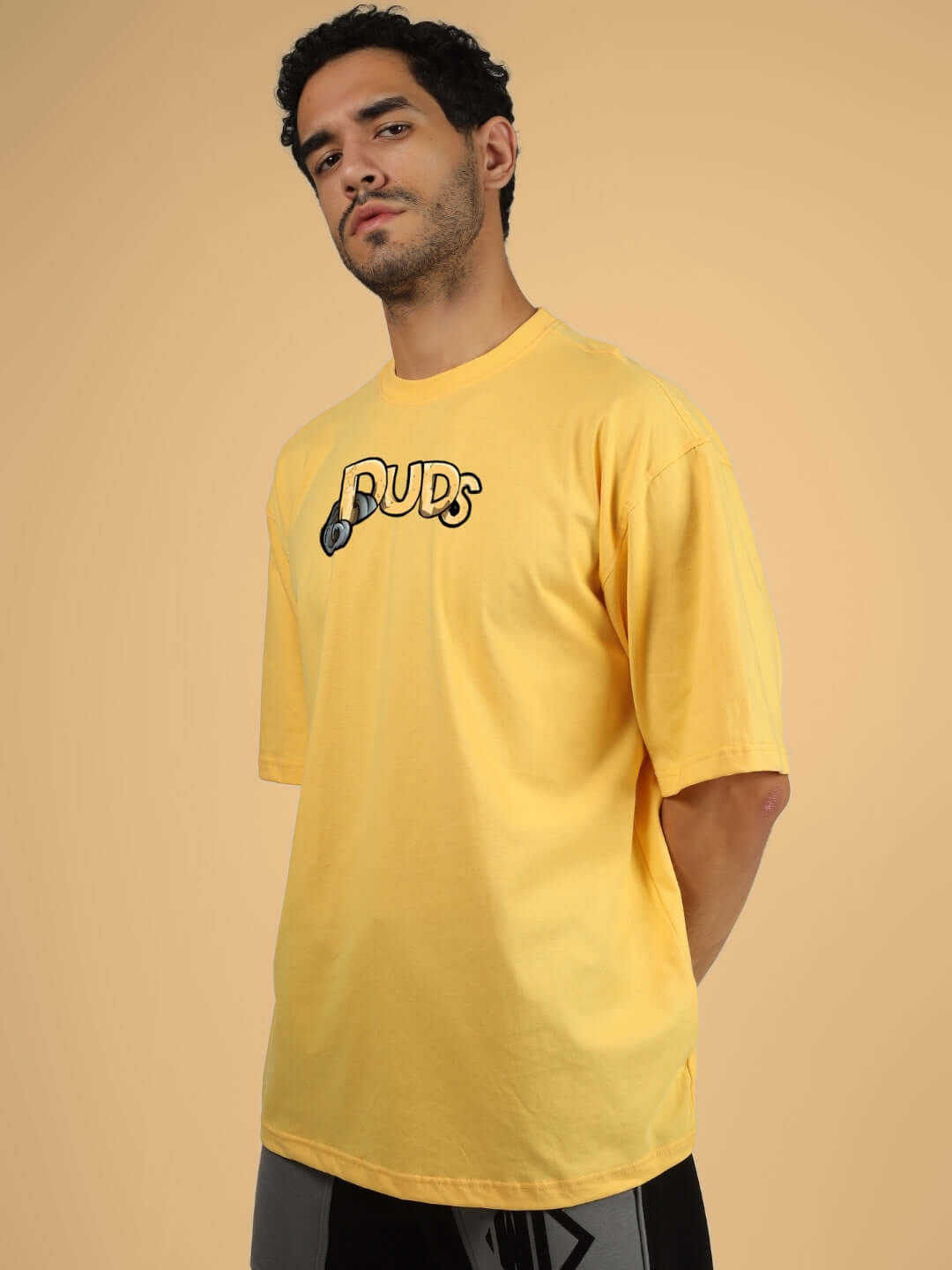 Model wearing DUCK TALES OVER-SIZED T-SHIRT YELLOW by DUDS, showcasing the casual design in a studio setting.
