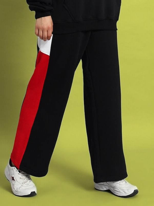 Woman wearing black colorblock cargo pants with red and white stripe, showcasing modern streetwear style.