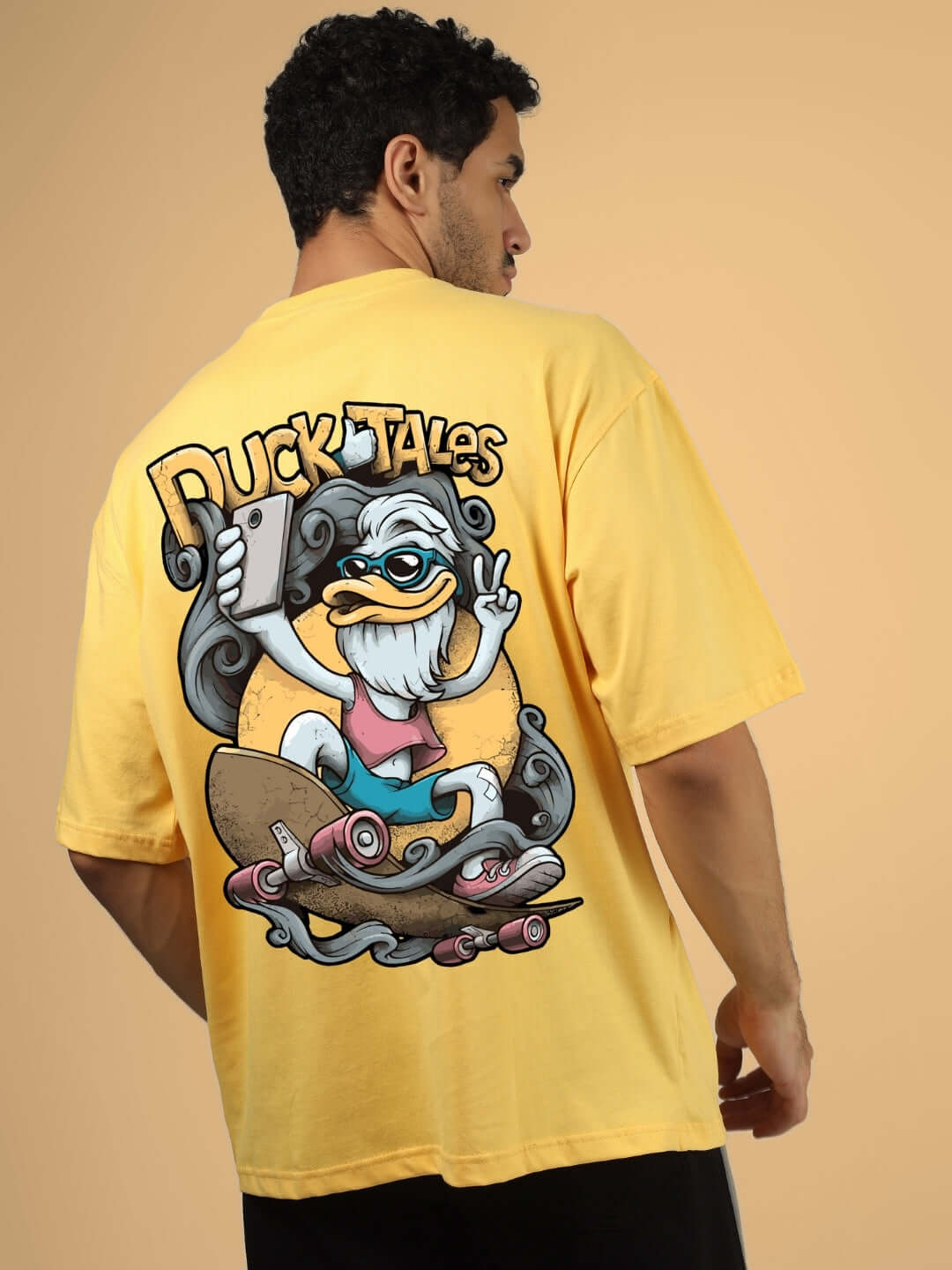 Man wearing DUCK TALES OVER-SIZED T-SHIRT YELLOW with cartoon graphic on back