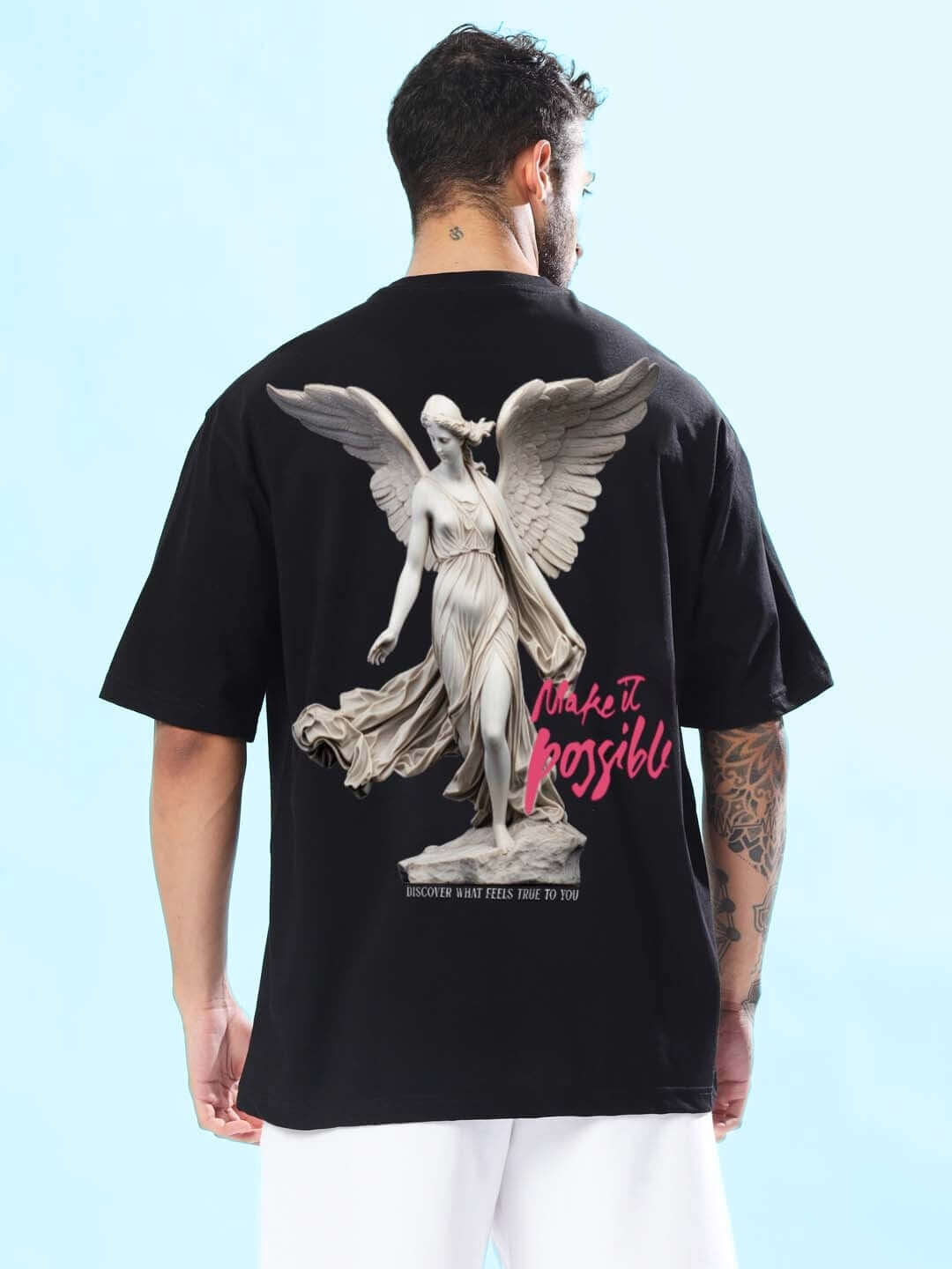 Back view of MAKE IT POSSIBLE OVER-SIZED T-SHIRT BLACK featuring a winged statue graphic and pink text.