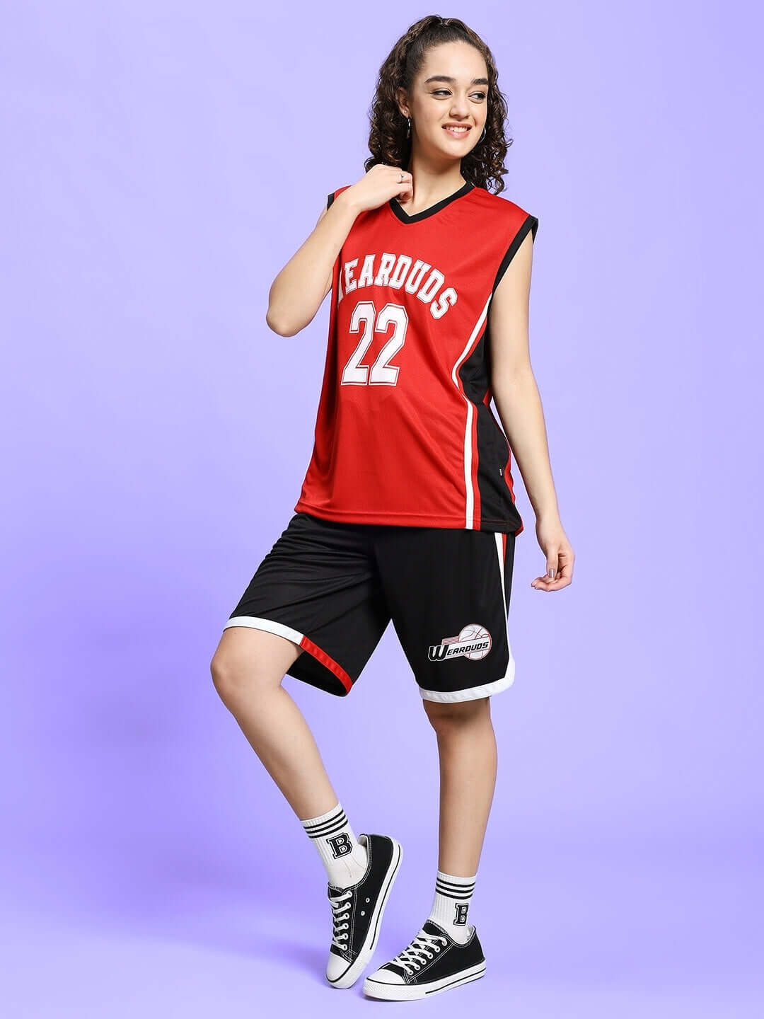 Woman wearing WOMEN PORTIA GYM CO-ORD SET in red and black, sports jersey with number 22, styled with sneakers. Ideal for athletic wear.