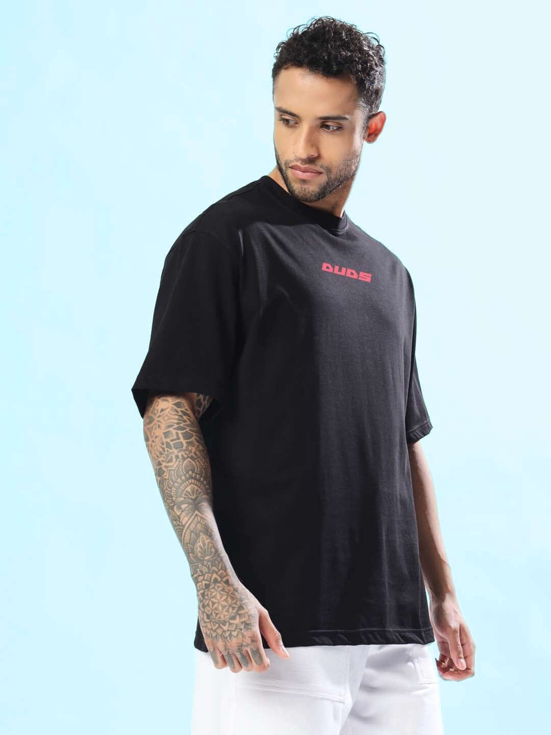 MAKE IT POSSIBLE OVER-SIZED T-SHIRT BLACK worn by model with tattooed arm, showcasing relaxed fit and stylish design.